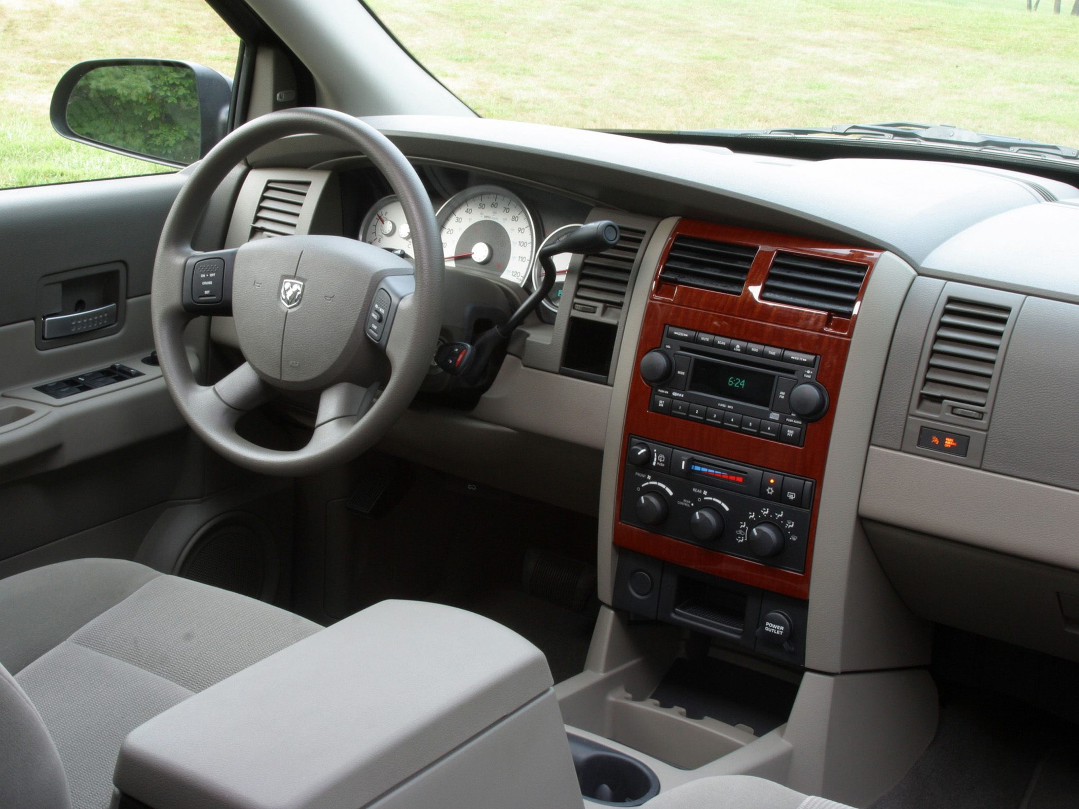 Beige SUV dashboard with wood trim, steering wheel, and center console controls