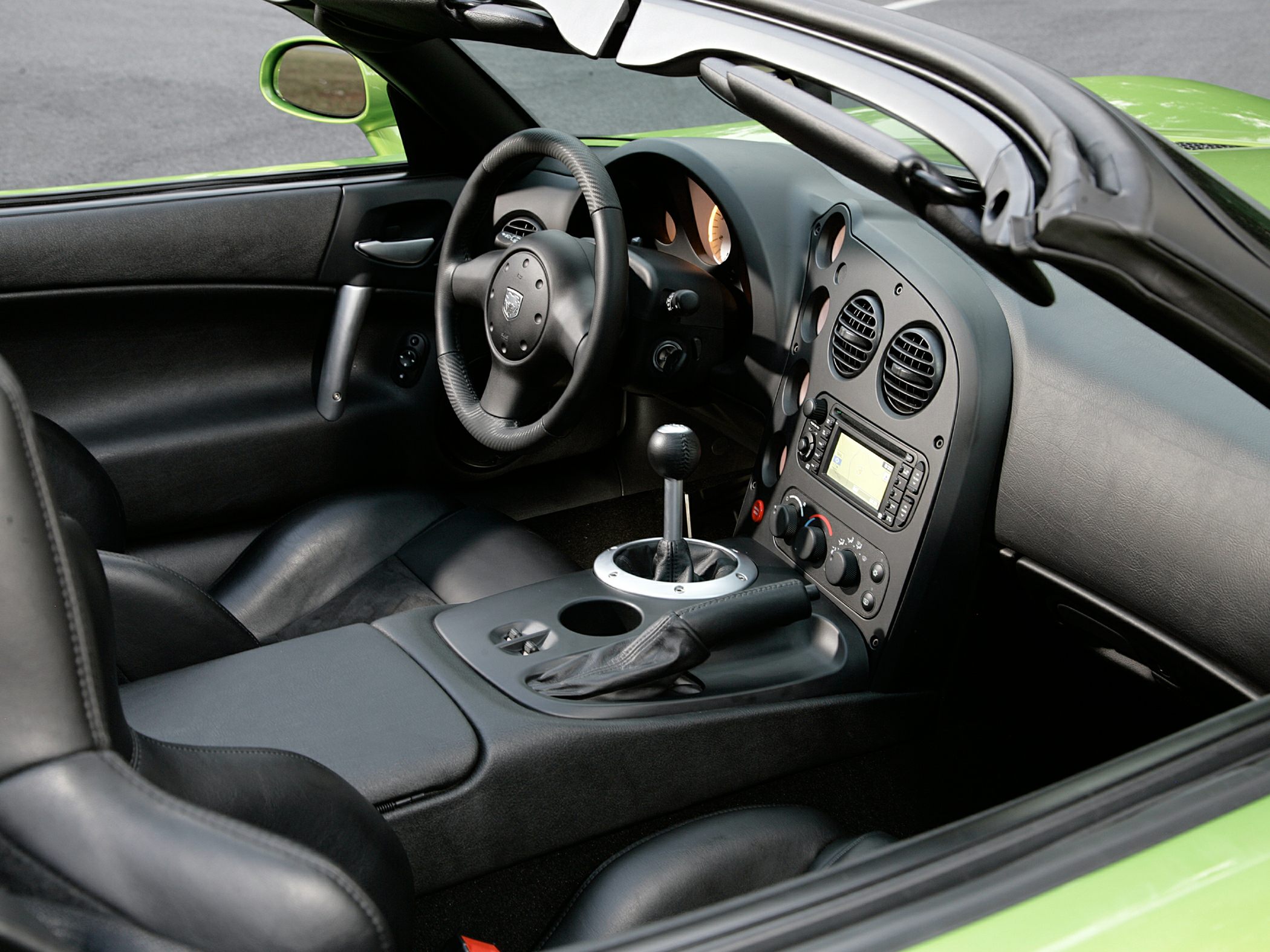 Manual gearshift, steering wheel, black leather seats, dashboard controls