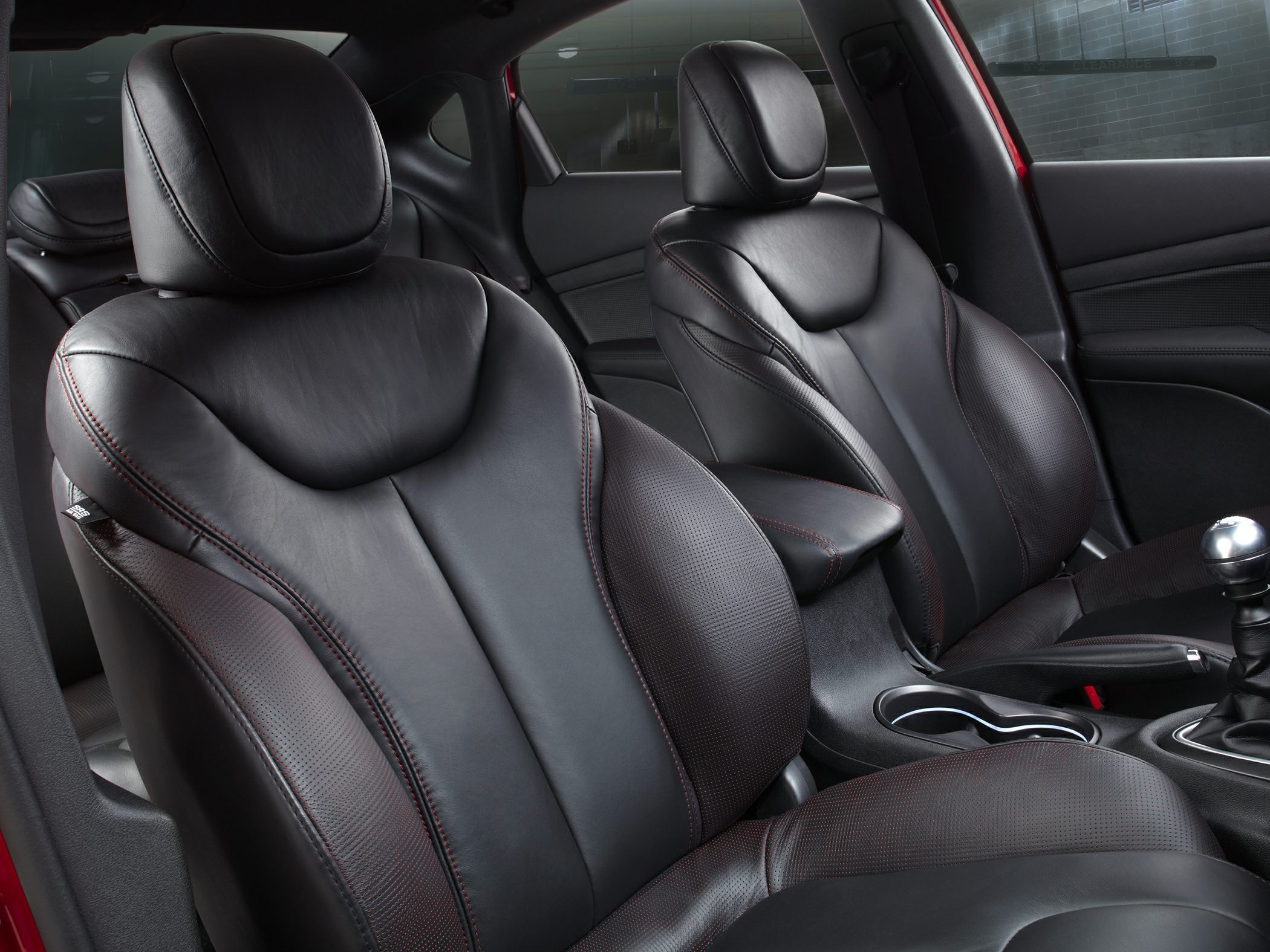Black leather front seats with red stitching and ergonomic design.