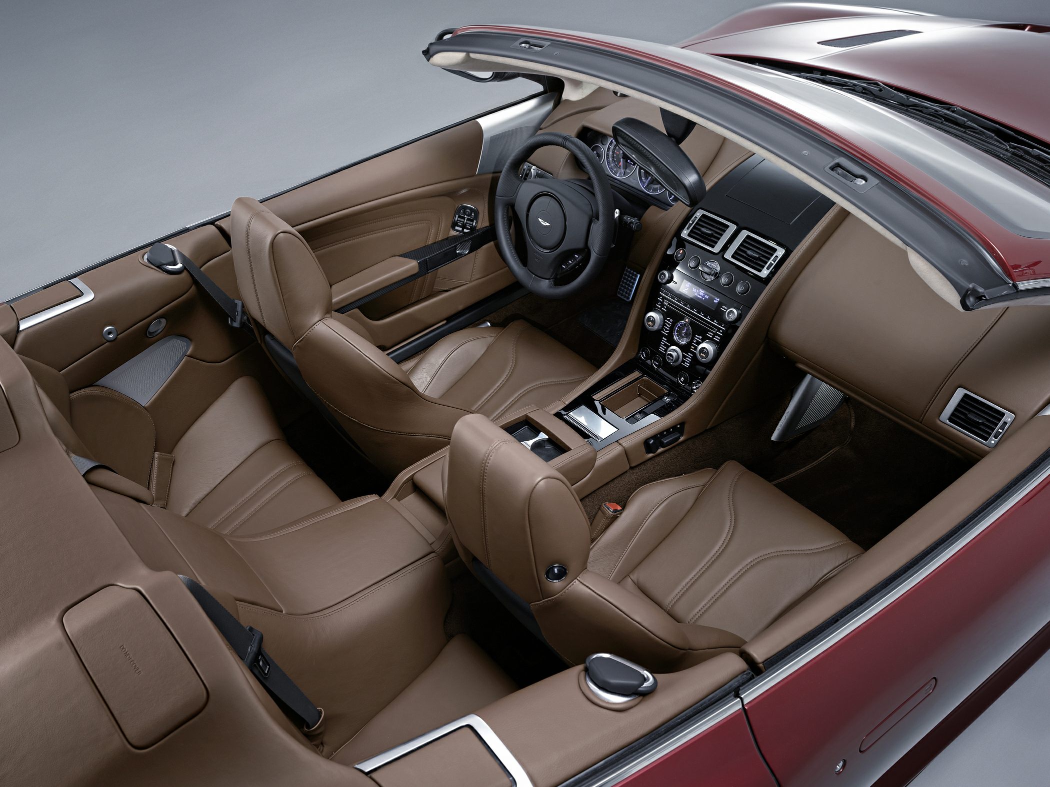 Brown leather interior of a luxury convertible with advanced dashboard and seating.