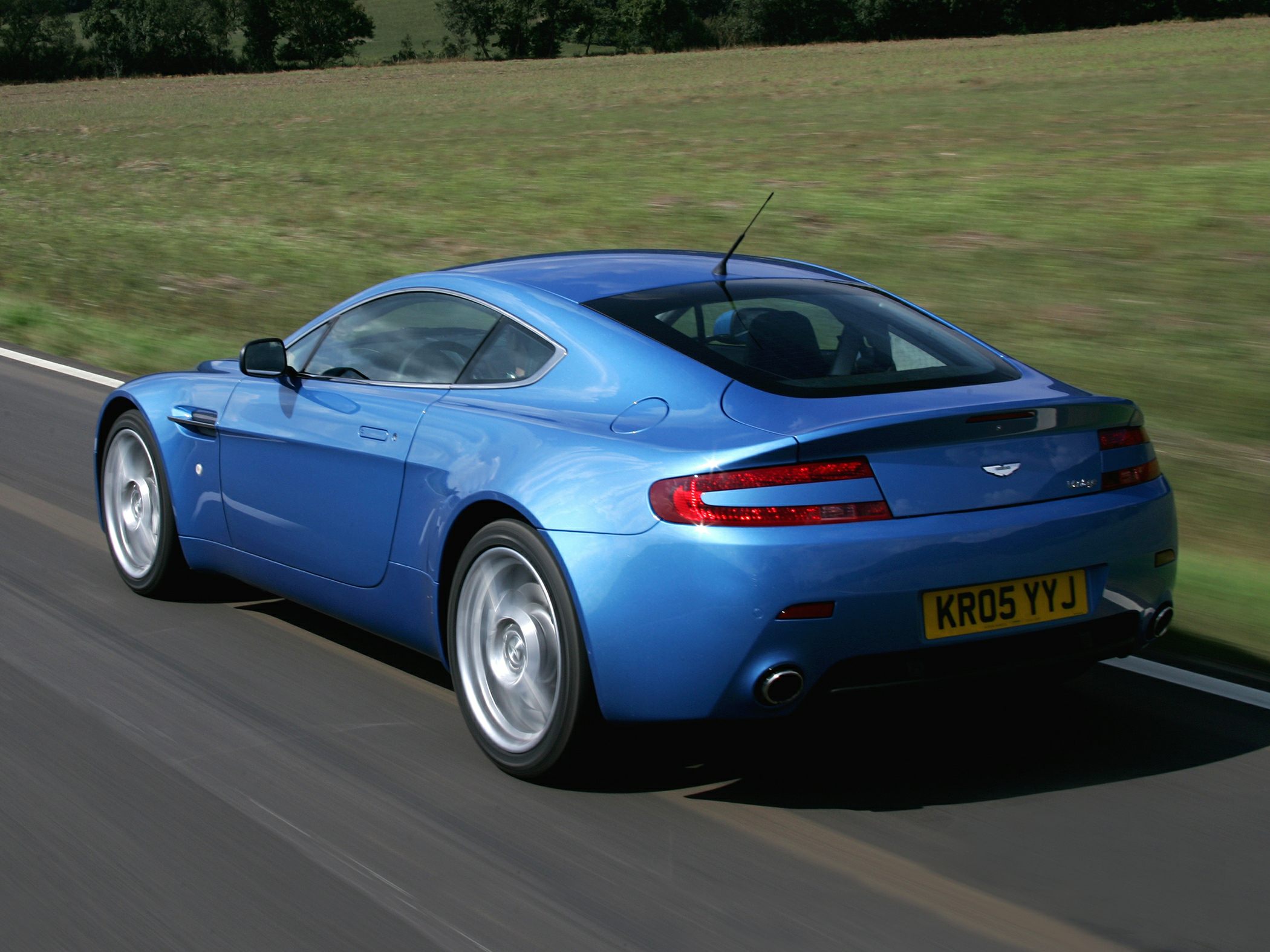 Blue luxury sports coupe rear side with dual exhaust and sleek aerodynamic design.