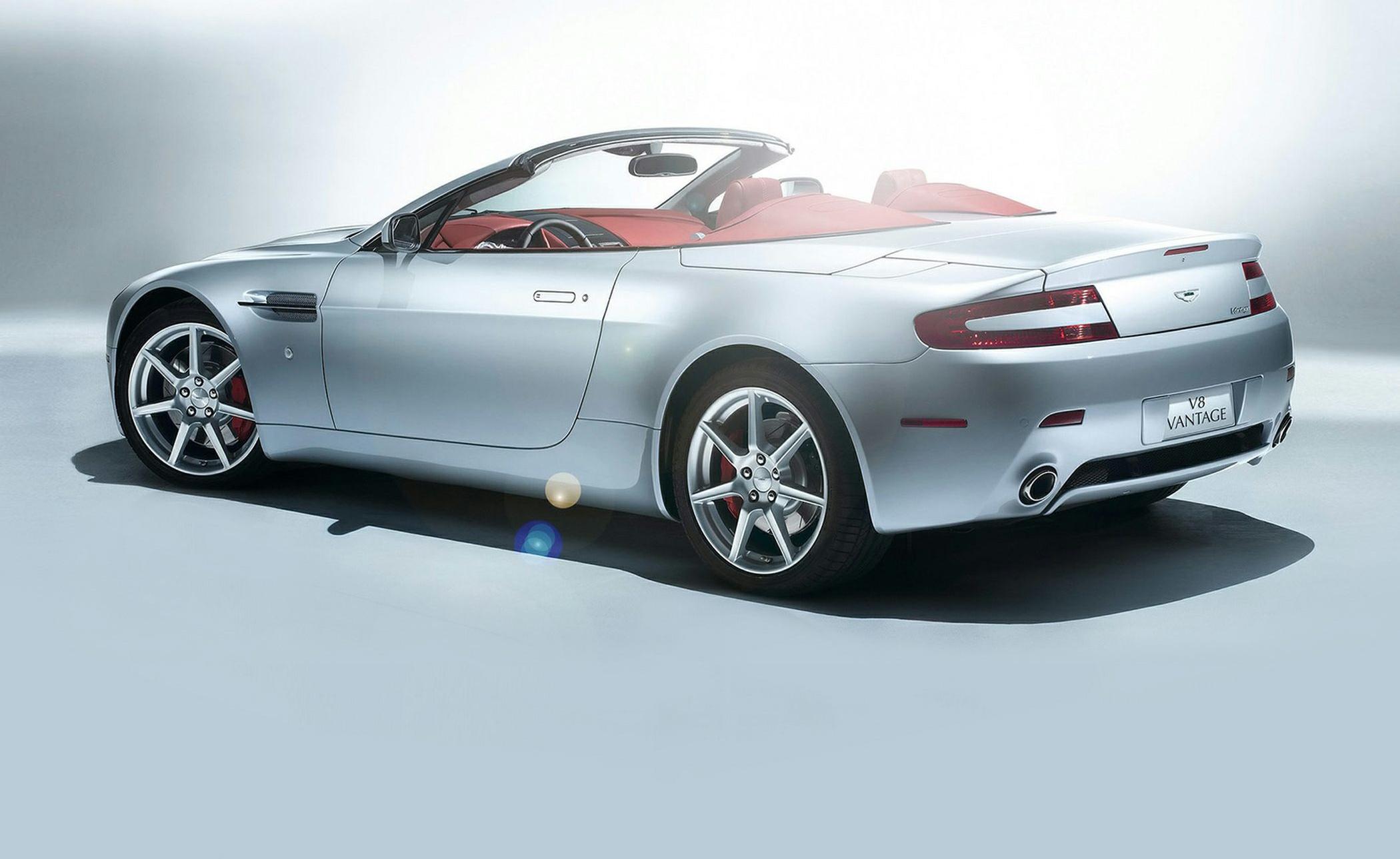Silver convertible with red interior, rear and side view.