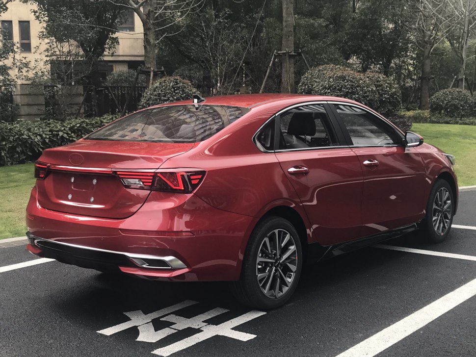 Rear and side profile of a red modern sedan with stylish tail lights and alloy wheels