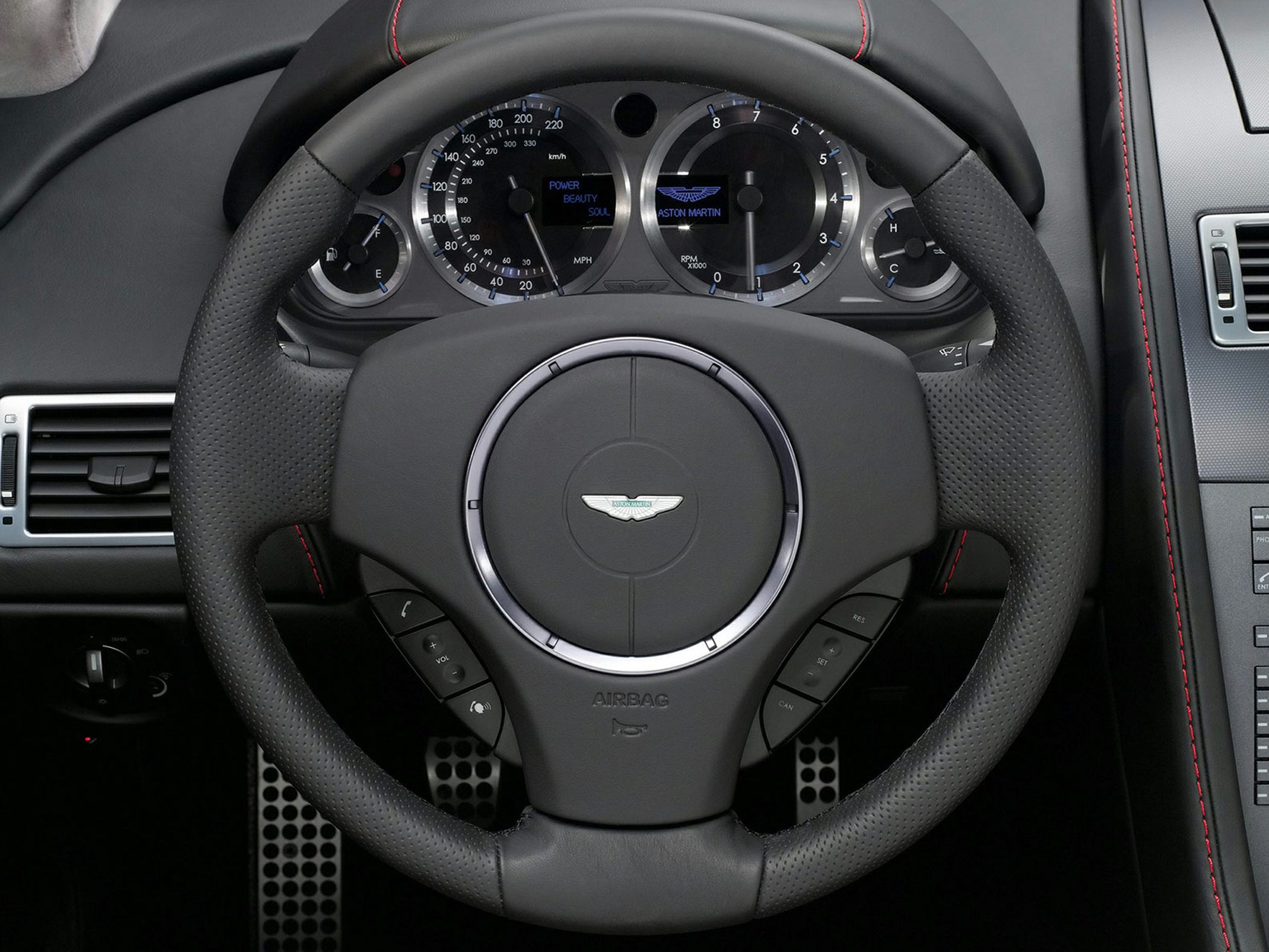 Luxury steering wheel with Aston Martin emblem and analog instrument cluster