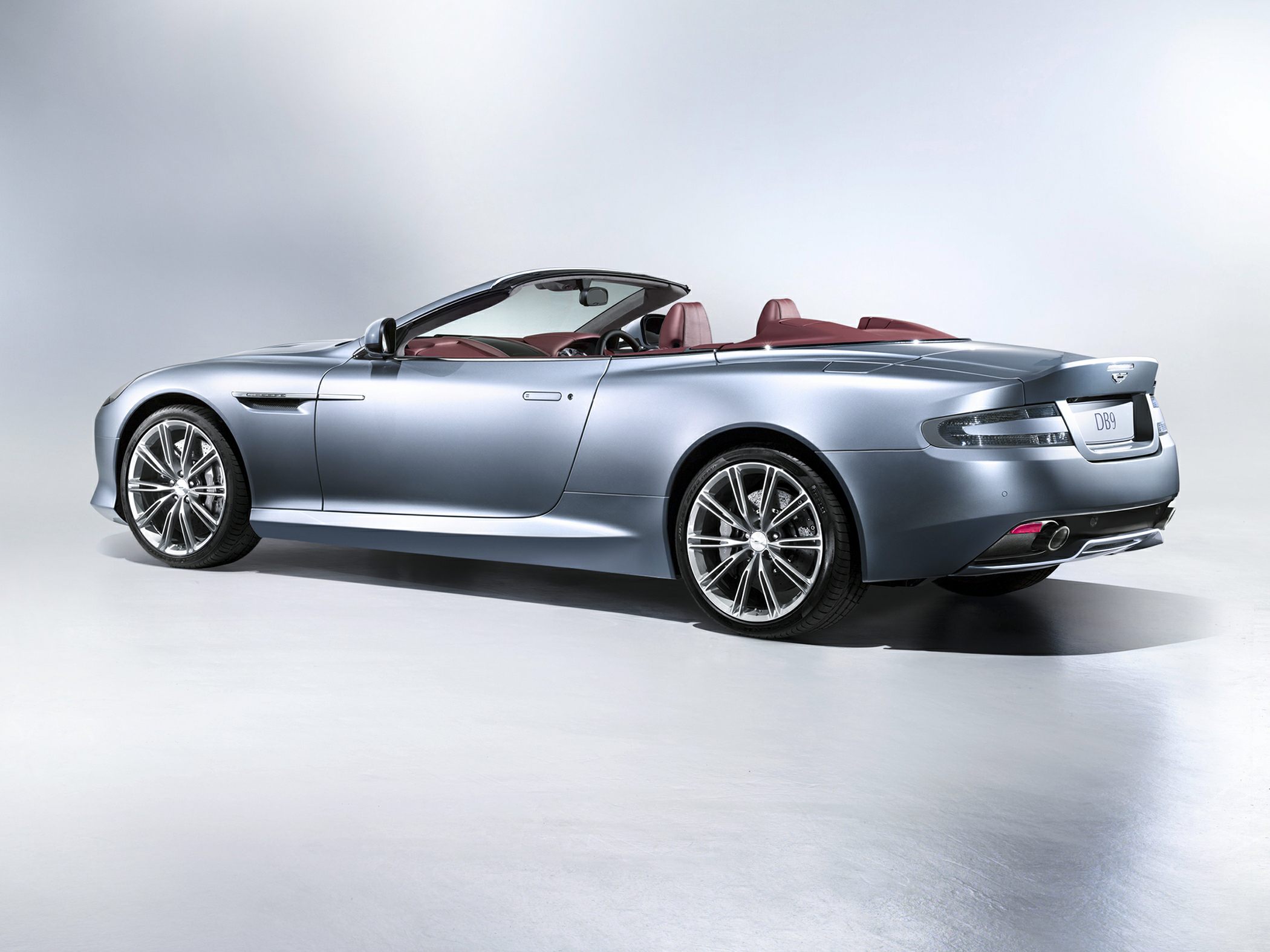 Convertible luxury sports car rear-side profile with open roof and alloy wheels