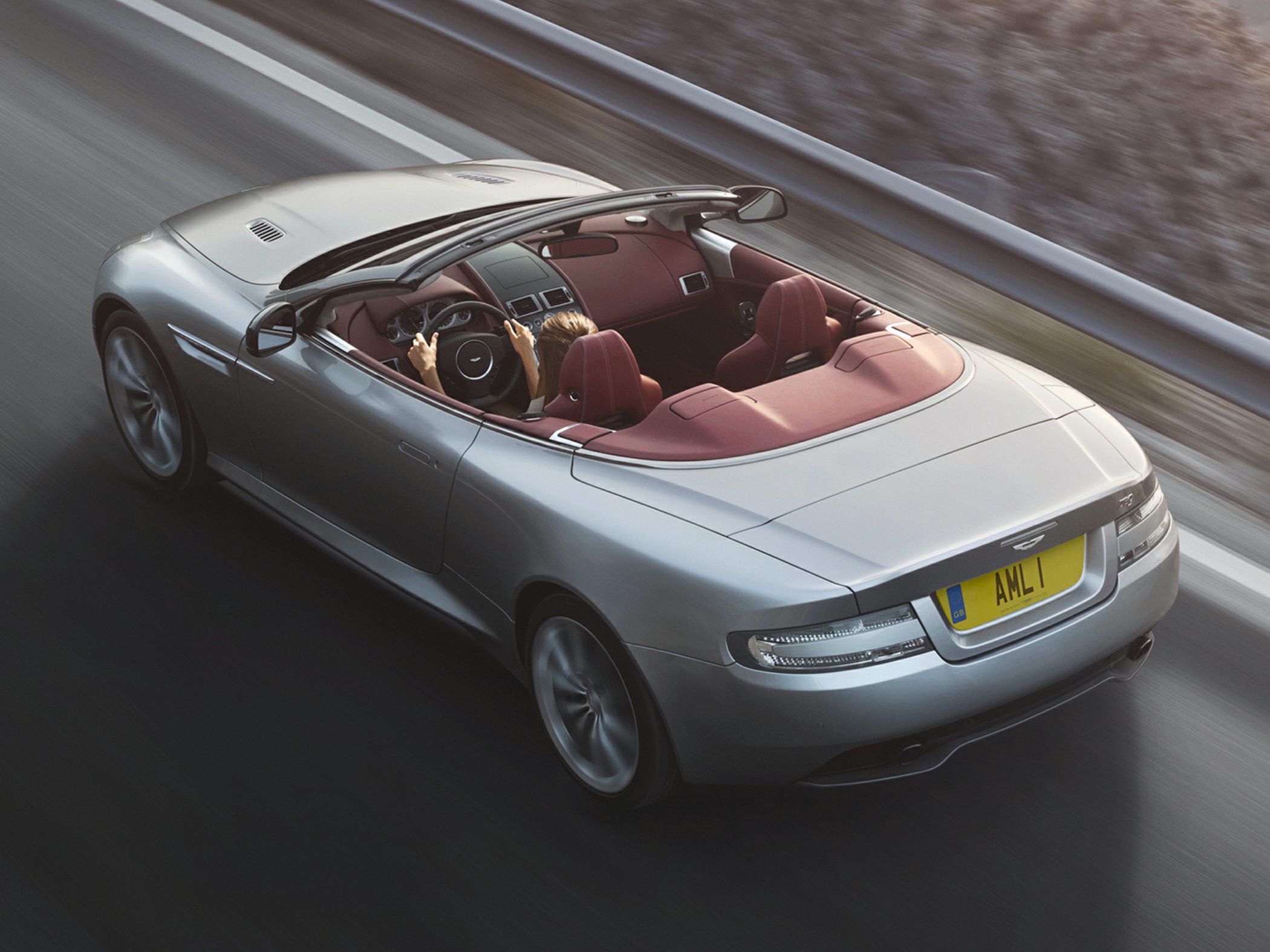Silver convertible with red leather interior driving on highway