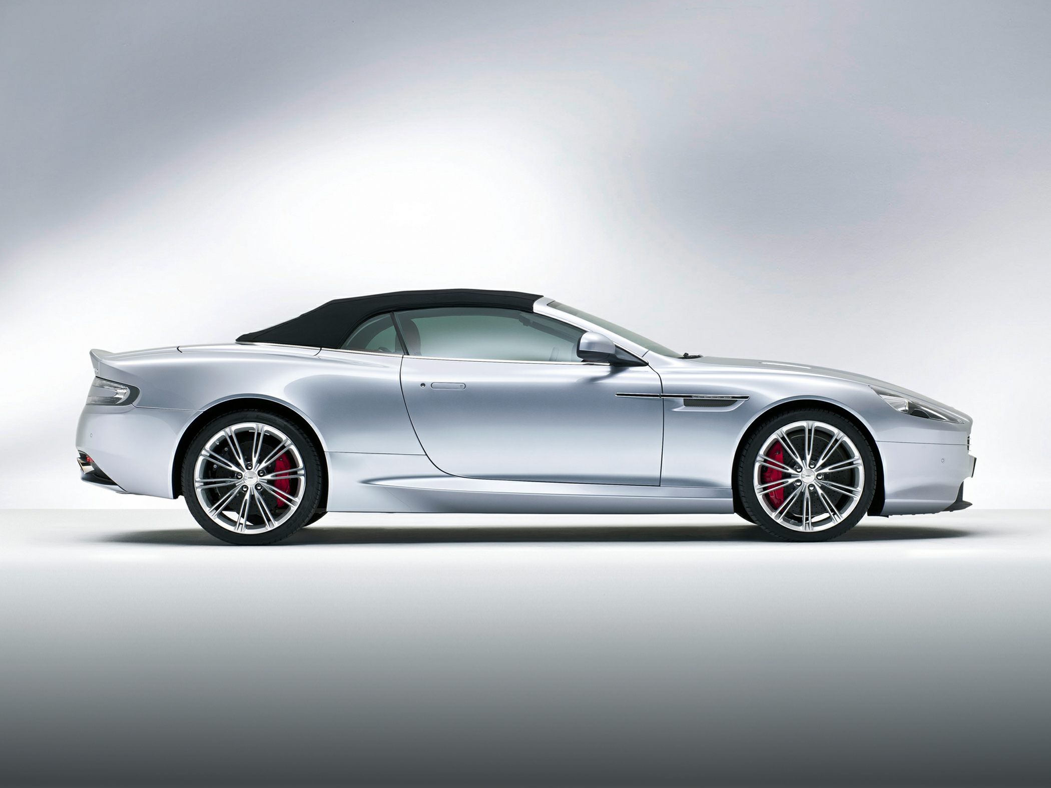 Silver convertible with soft top and alloy wheels, side profile view