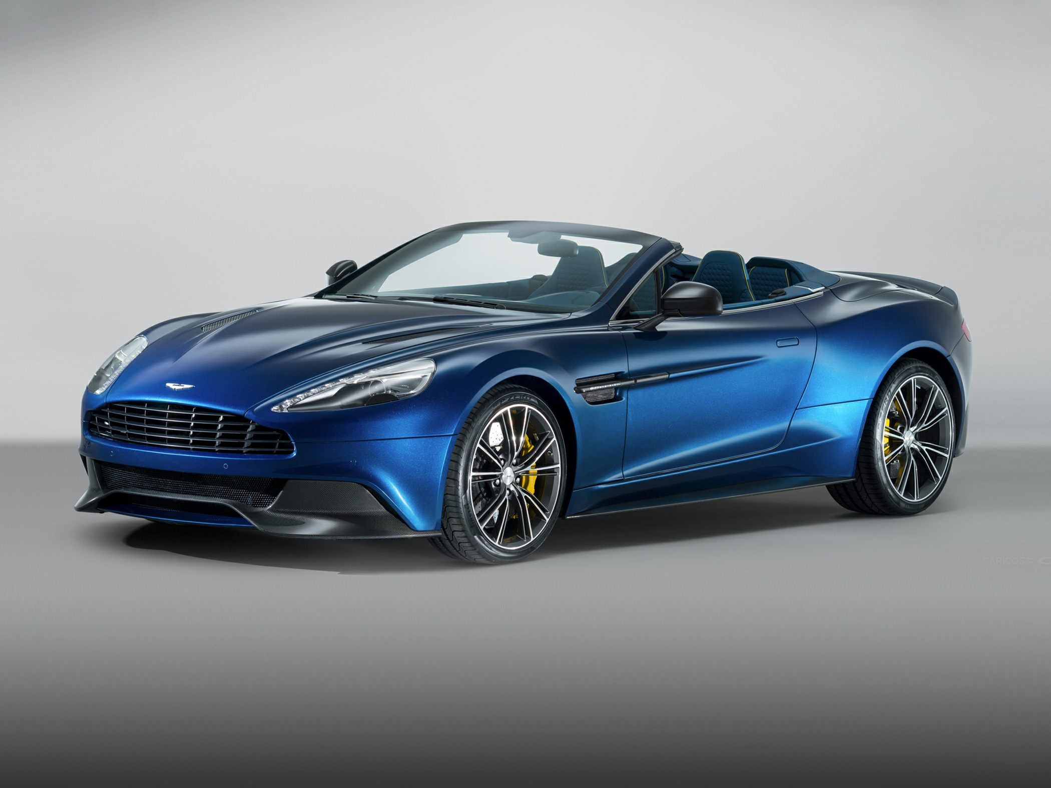 Blue luxury convertible with sharp headlights and sporty rims, front side view.