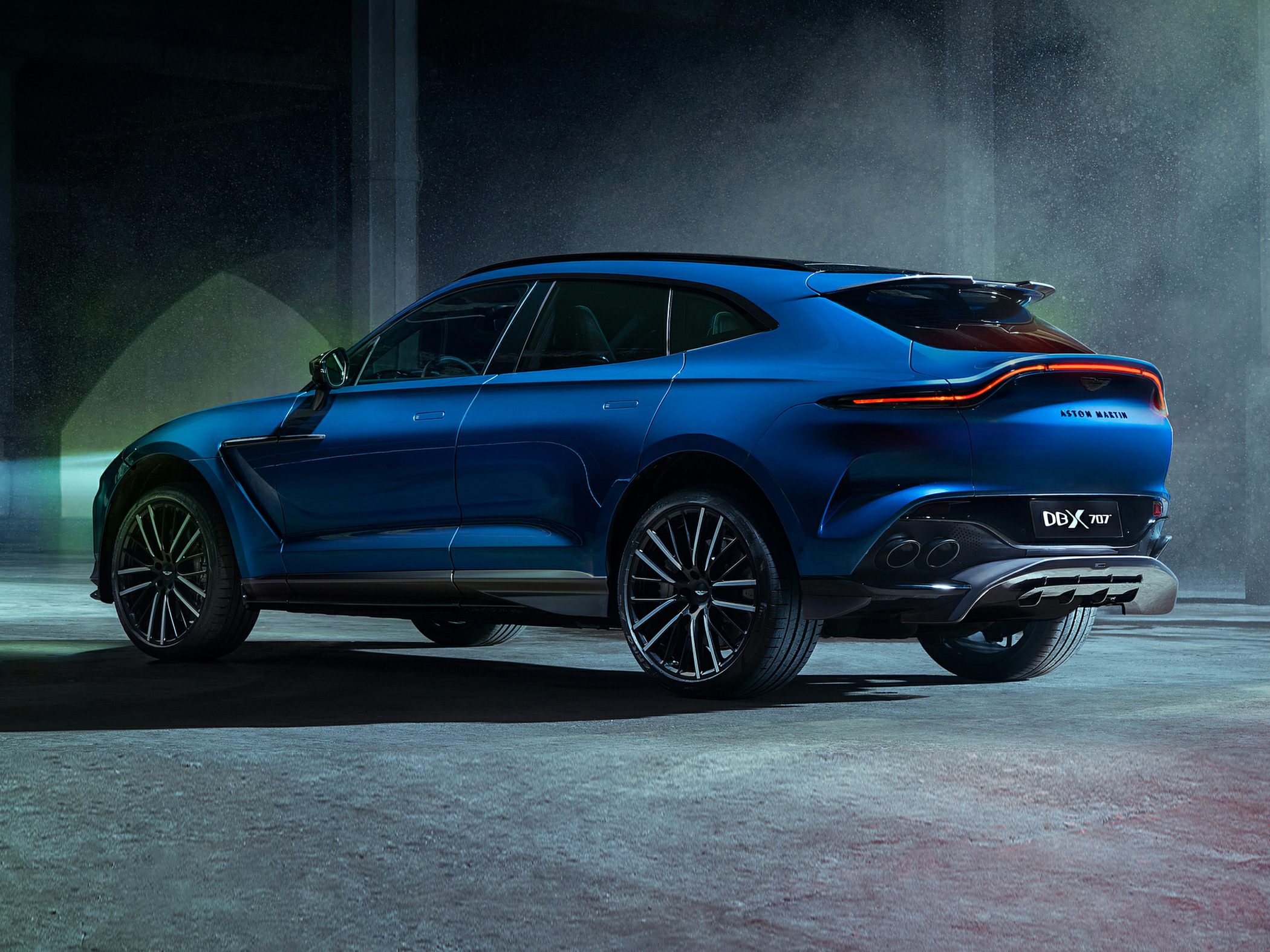 Sleek rear and side profile of a blue luxury SUV with distinctive rear lights and quad exhaust