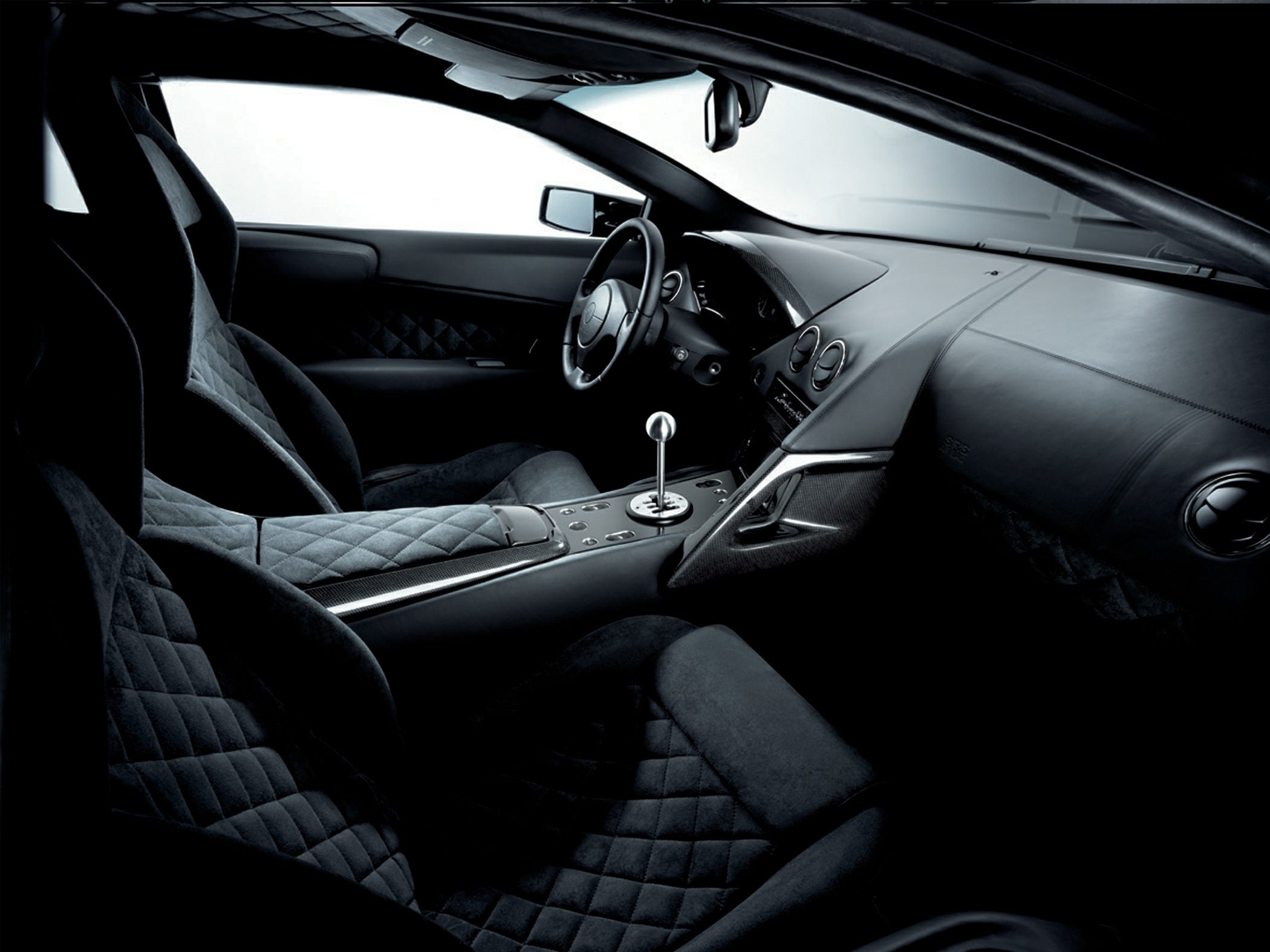 Quilted seats and iconic gated manual shifter in dark luxury sports car interior