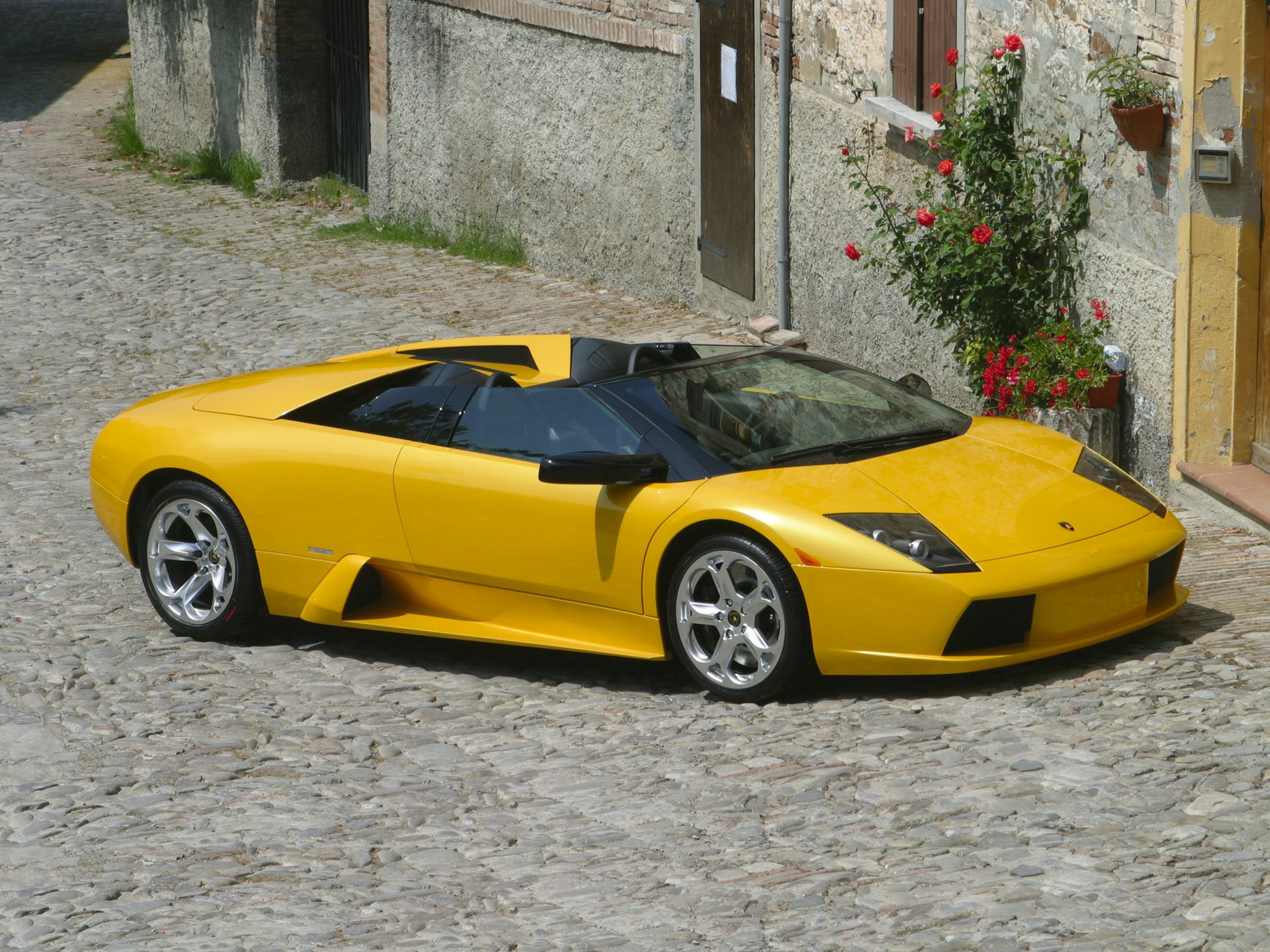 Yellow convertible sports car with sharp angular headlights and alloy wheels
