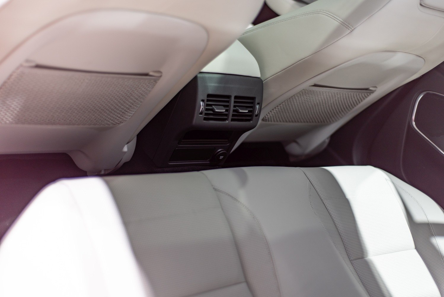 Rear air vents and light-colored leather seats with mesh seatback pockets.