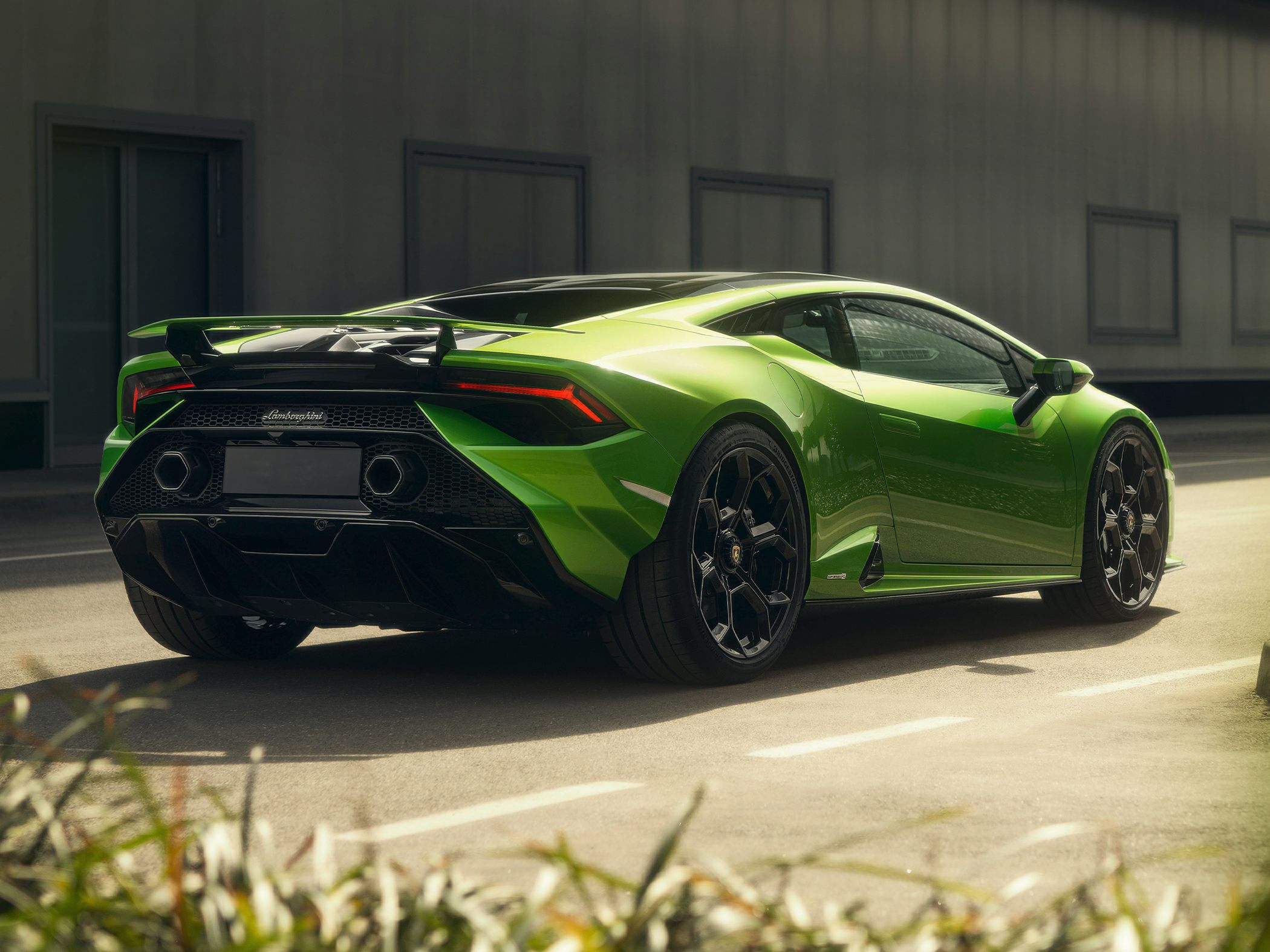 Rear view of green sports car with rear spoiler and hexagonal dual exhaust