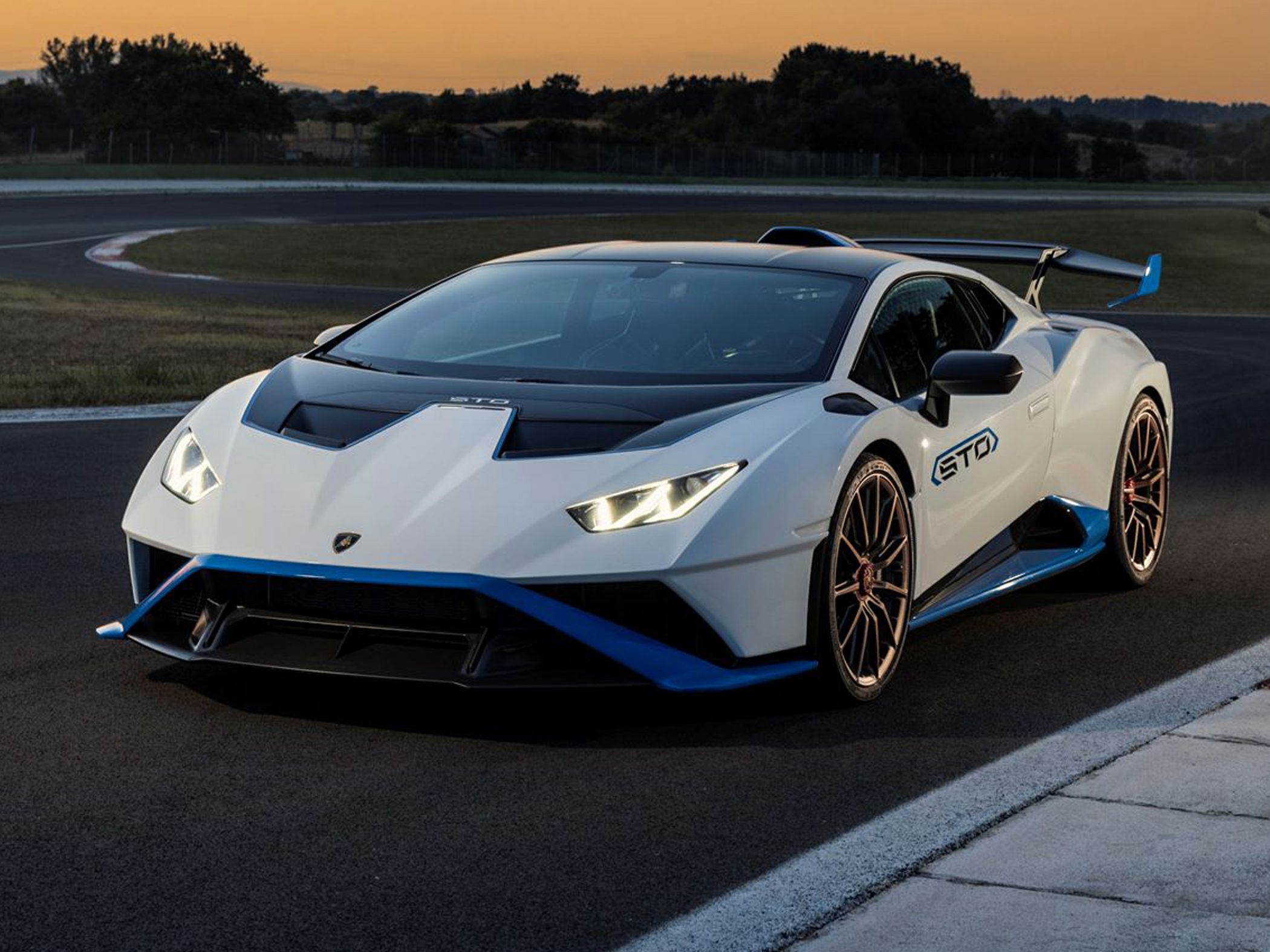 Front view of aerodynamic sports car with sharp headlights and race track setting