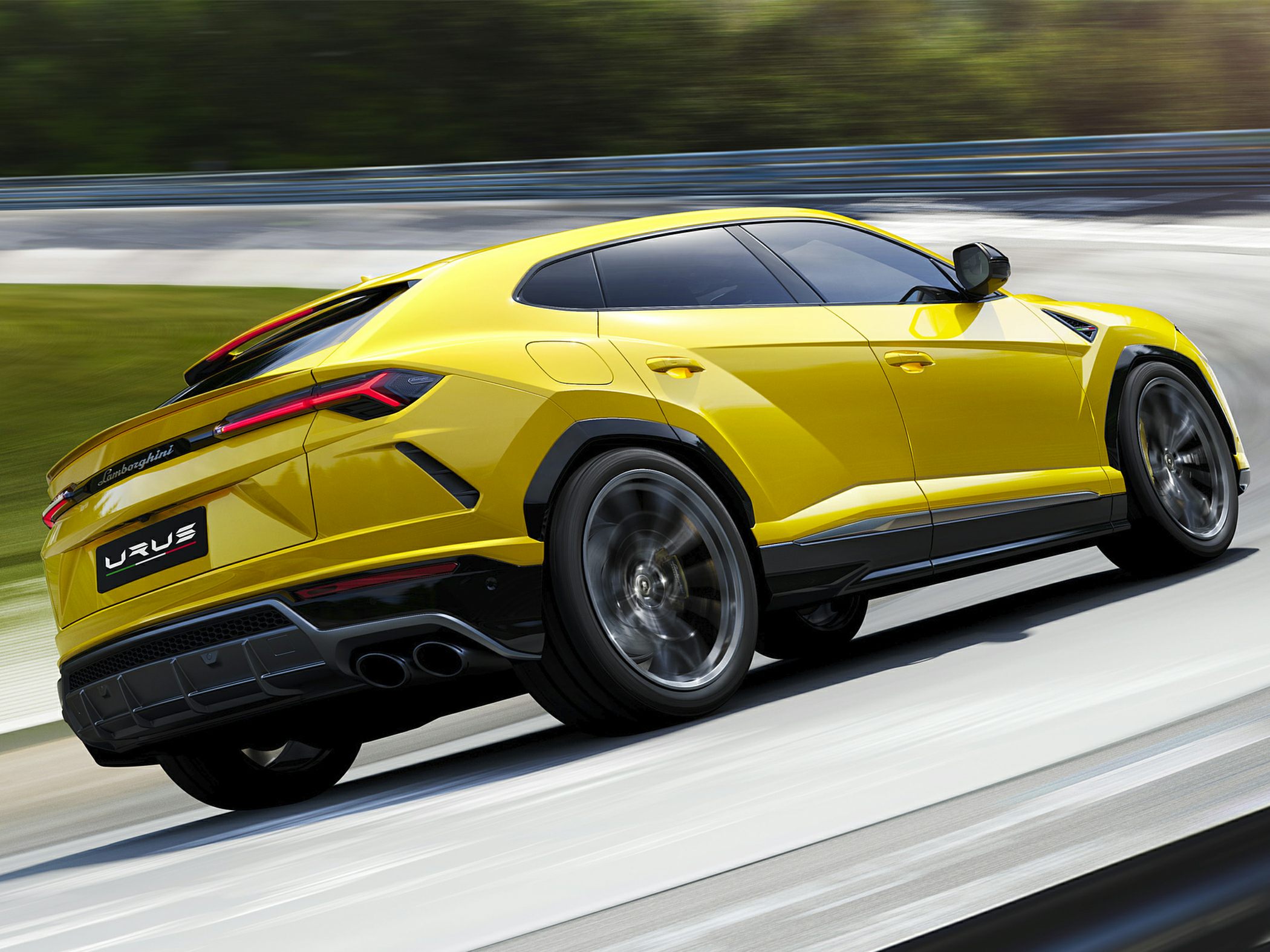 Rear-side view of yellow Lamborghini Urus in motion