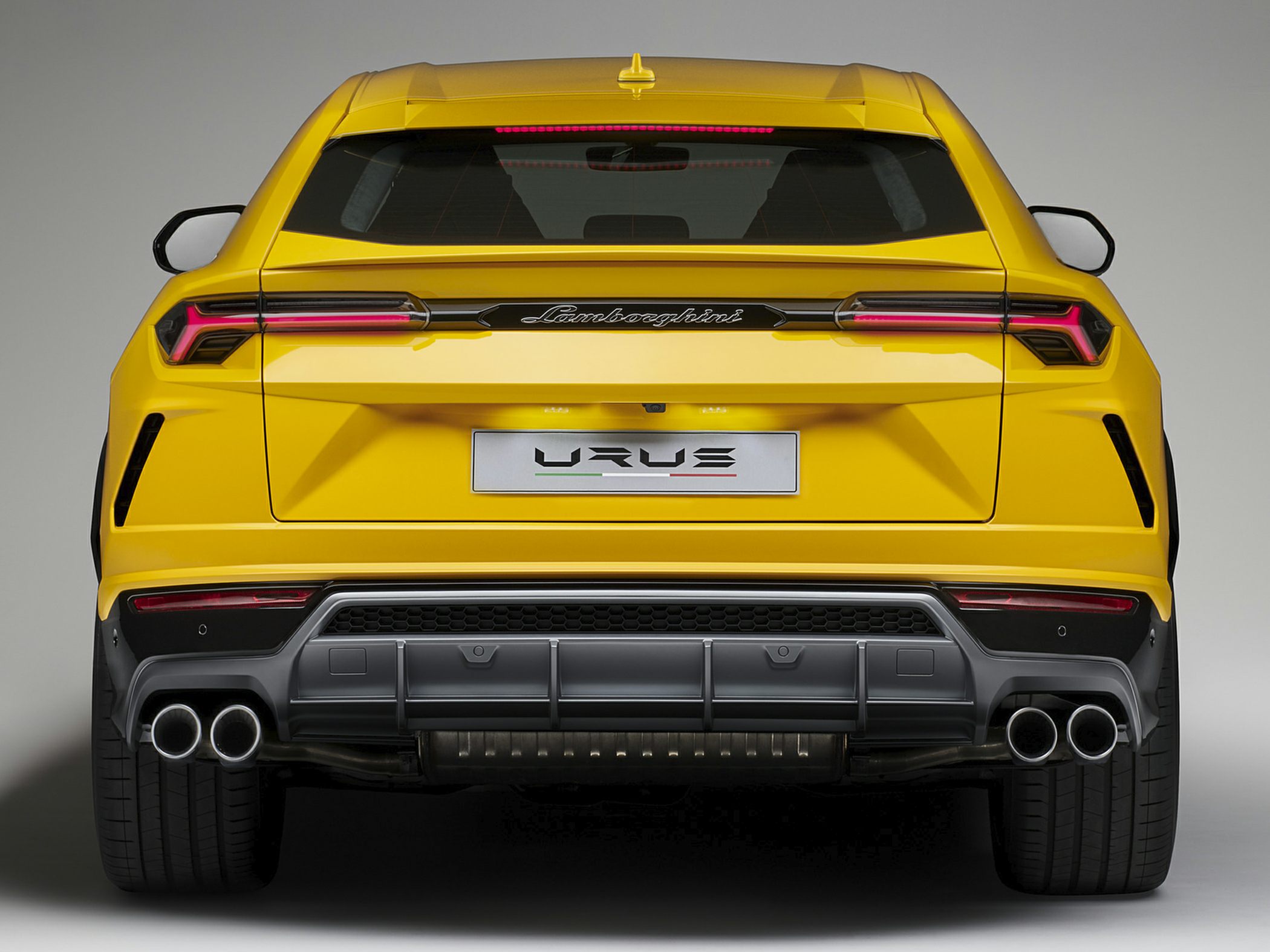 Rear view of yellow SUV with quad exhaust tips and distinctive LED taillights