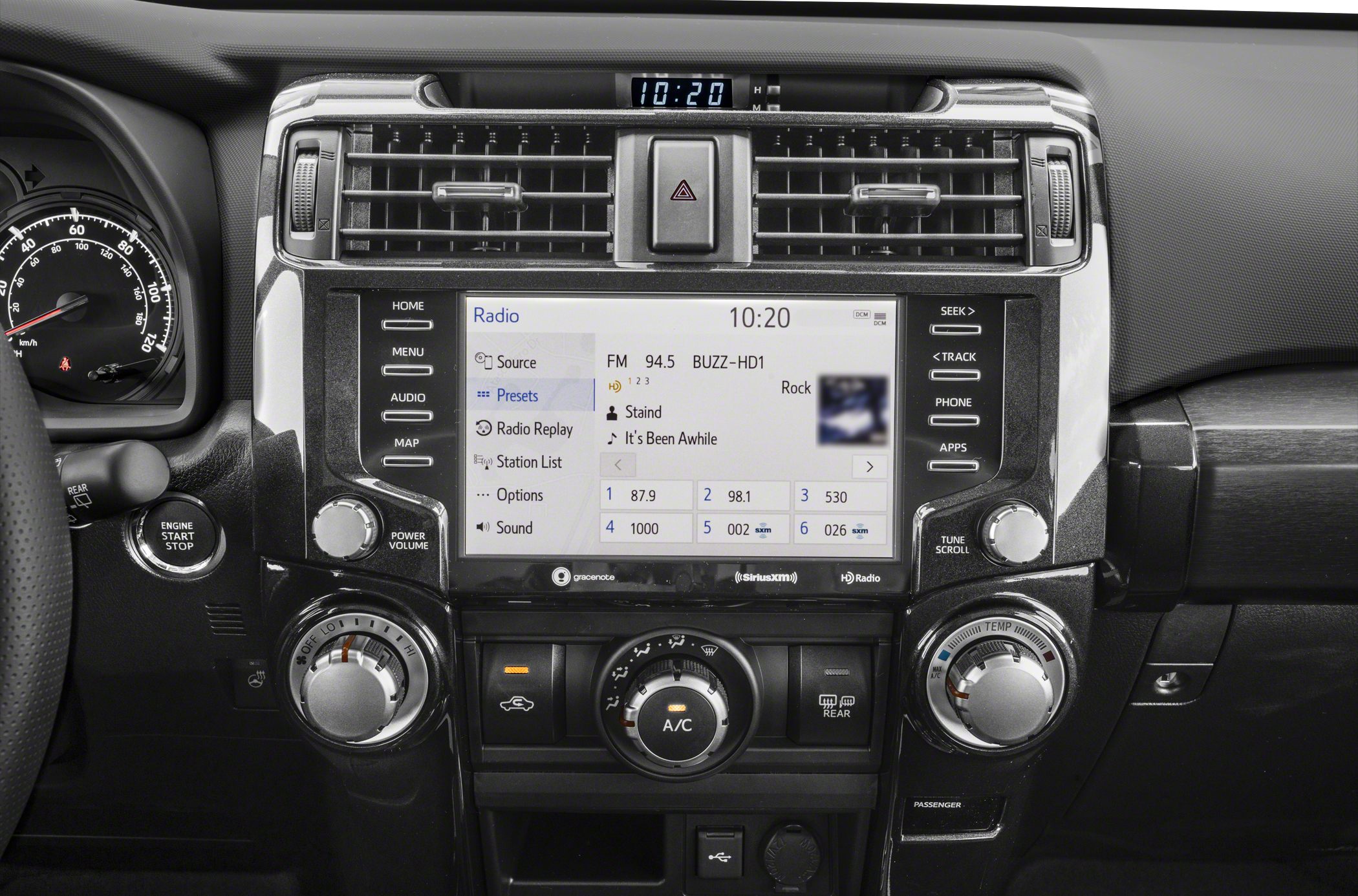 Infotainment touchscreen and three climate control knobs on a car dashboard
