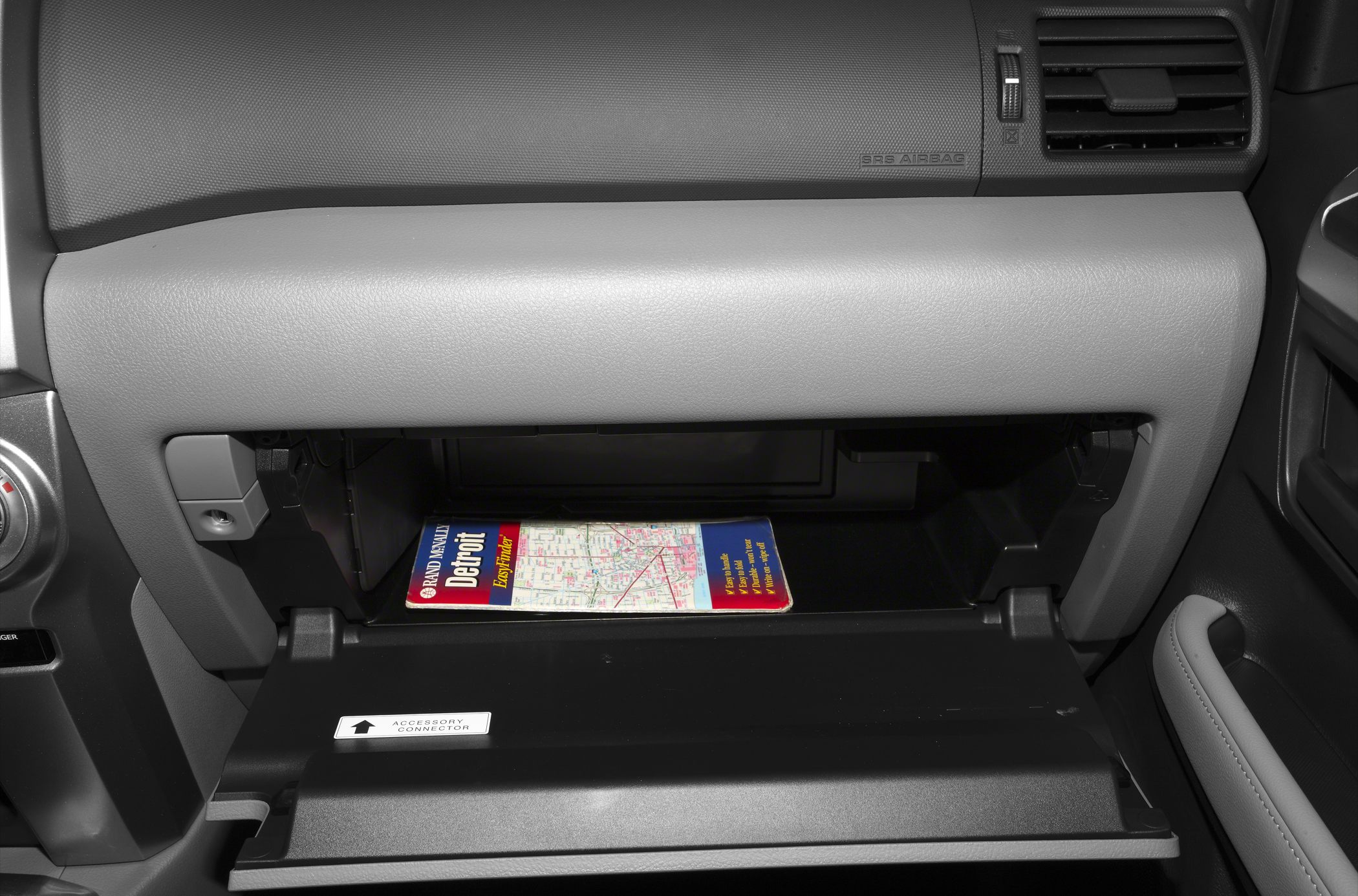Open glove compartment with map inside in vehicle interior