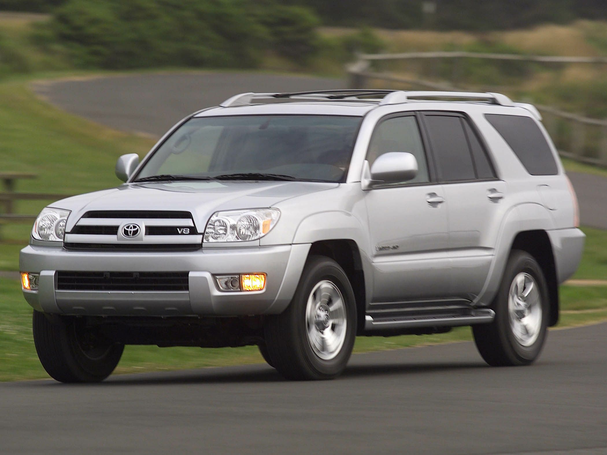 Silver SUV with V8 badge, prominent grille, alloy wheels, and roof rack