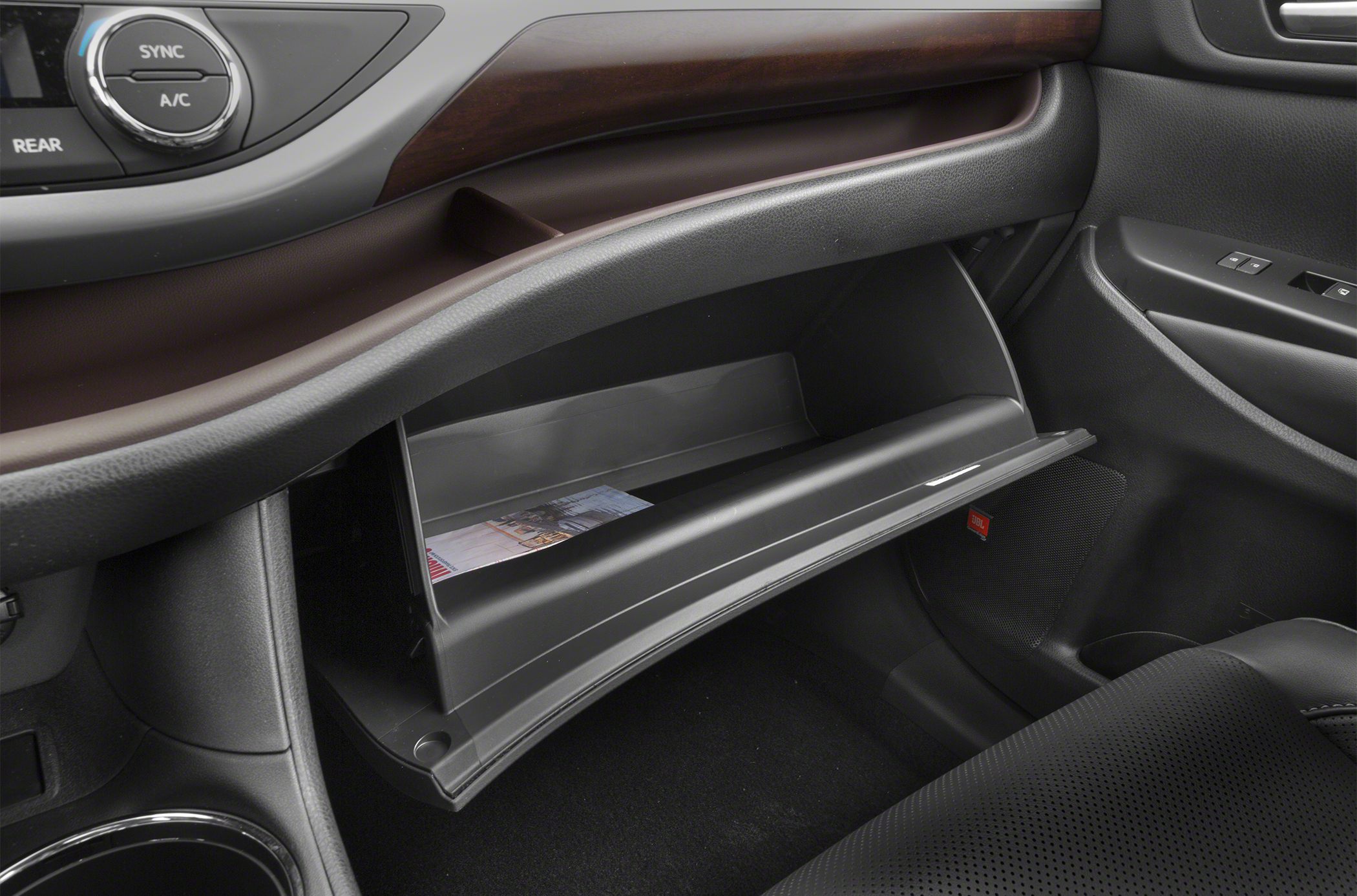 Open glove compartment and dashboard with controls and door panel inside vehicle.