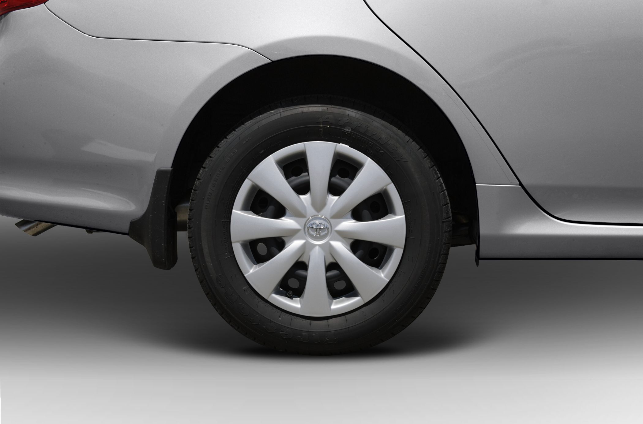 Rear wheel with hubcap and quarter panel of a silver vehicle.