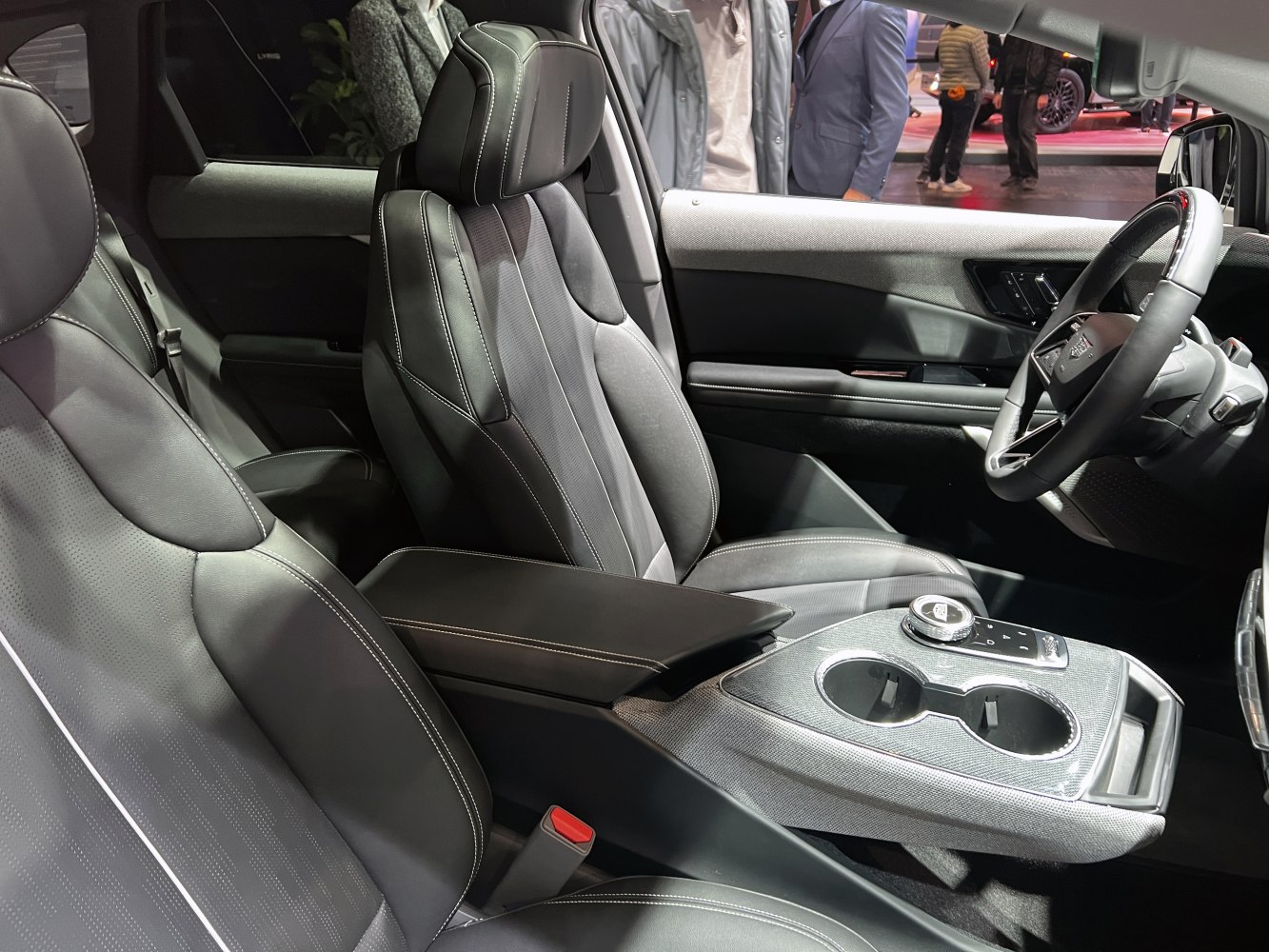 Close-up of front seats and center console with armrest and cup holders.