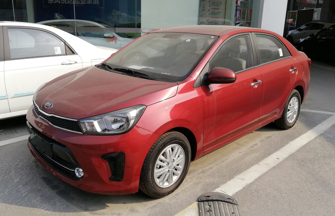Front-side view of red compact sedan with modern headlights and grille