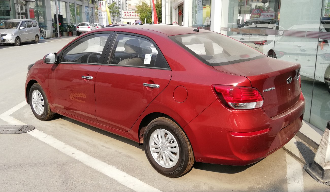 Rear side view of red sedan with alloy wheels and chrome handles