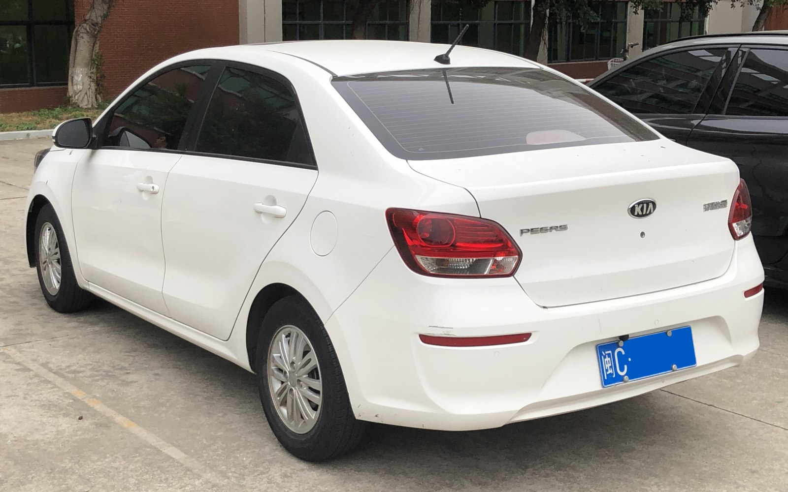 Rear and side profile of a white compact sedan with distinct taillights