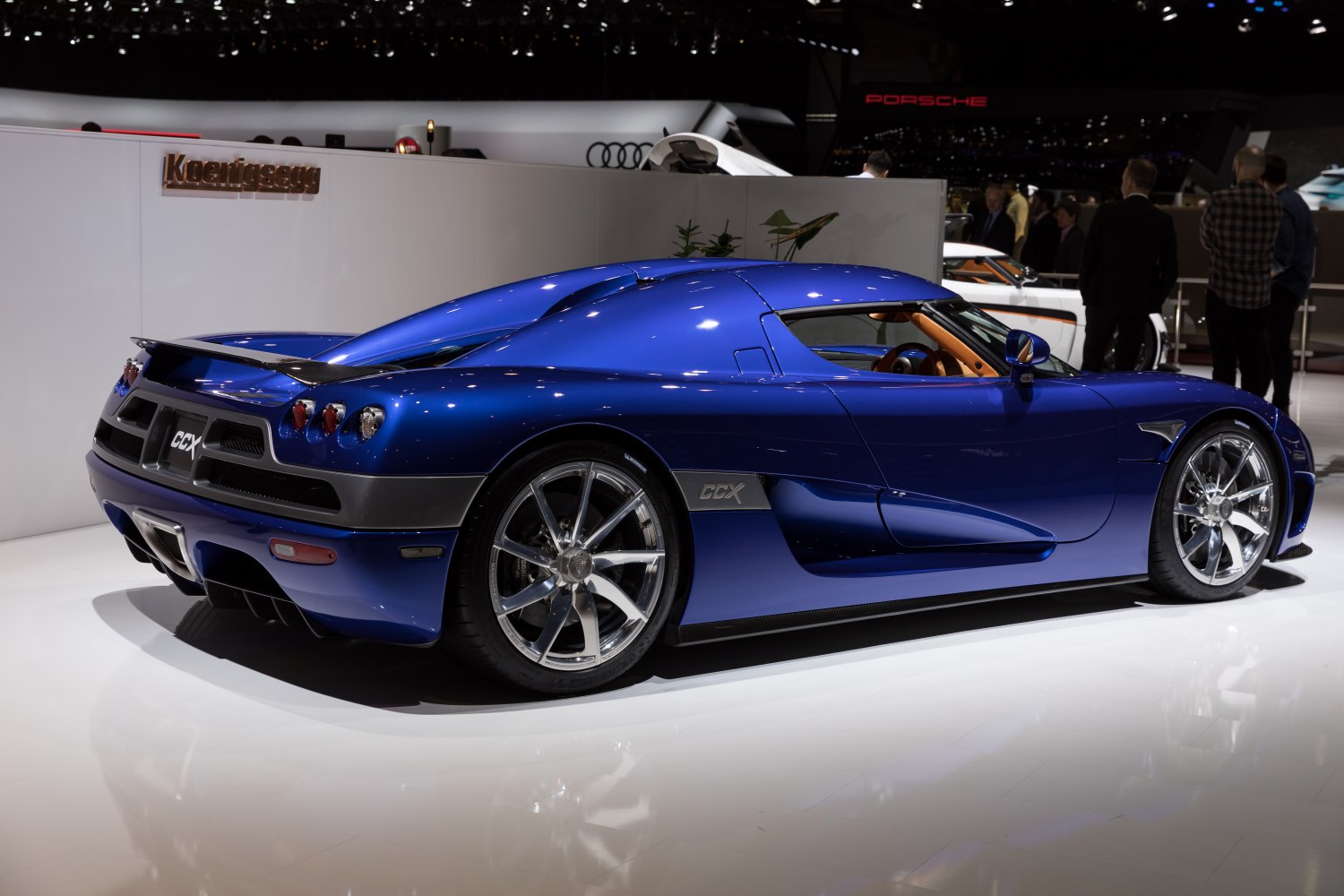 Blue sports car rear side profile with chrome alloy wheels and aerodynamic body.