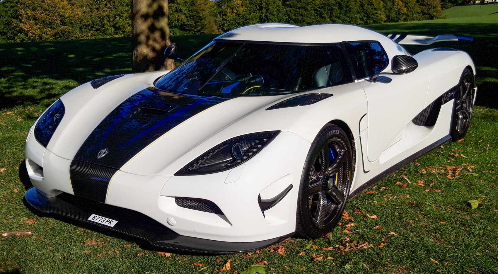 White sports car with carbon fiber hood and rear wing spoiler
