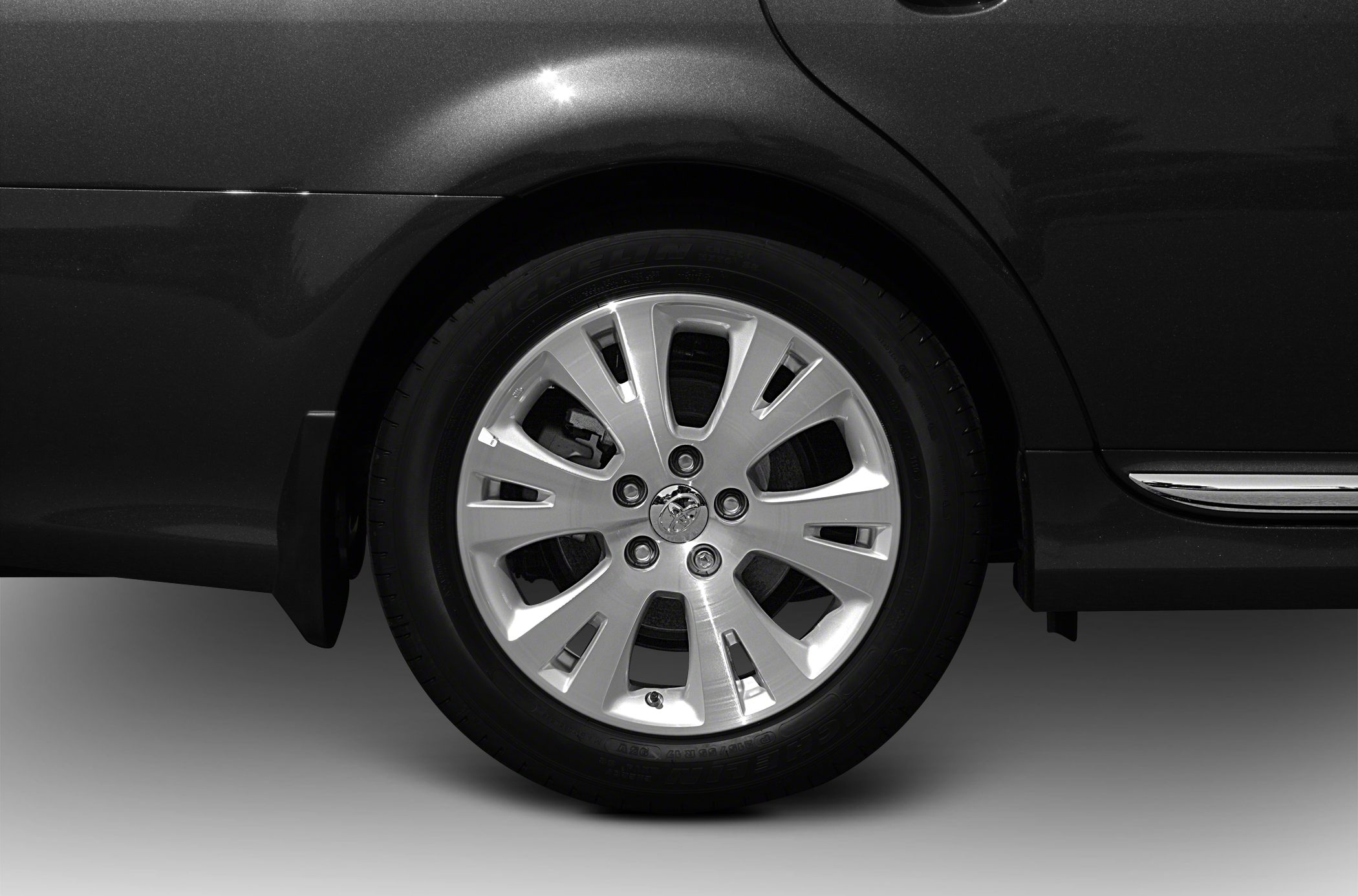 Close-up of alloy wheel and tire tread on car rear side.