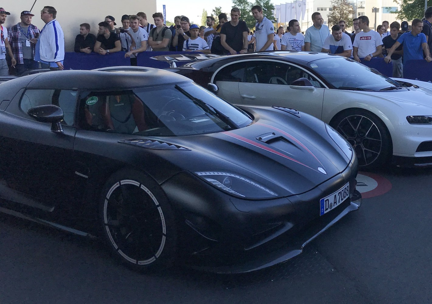 Matte black hypercar front side with aerodynamic vents and red racing stripes