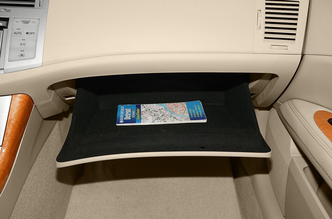 Open glove compartment with a map inside within beige car interior