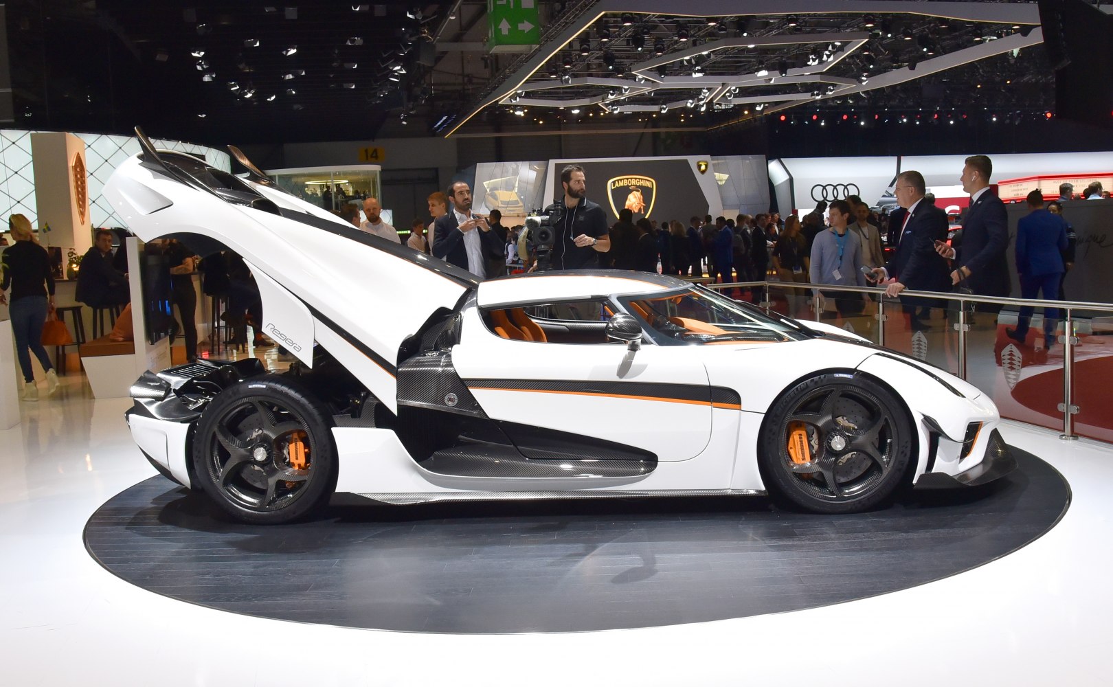 Side view of a white supercar with rear hatch open and carbon fiber details