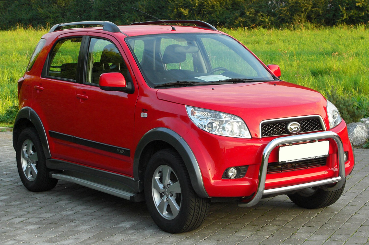 Red compact SUV with bull bar, roof rails, and alloy wheels.