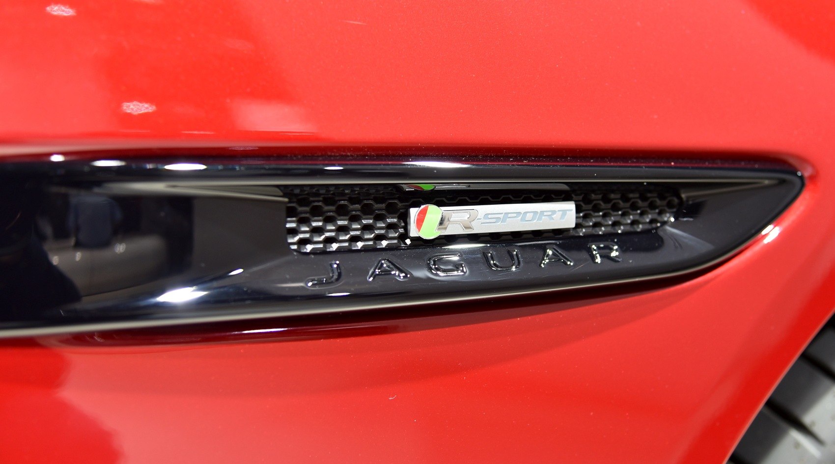Close-up of R-Sport badge with Jaguar on black trim.