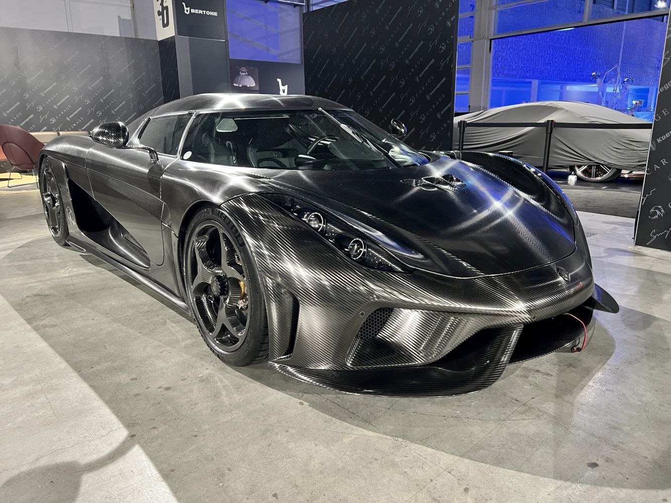 Front side view of a carbon fiber hypercar with aerodynamic design and LED headlights