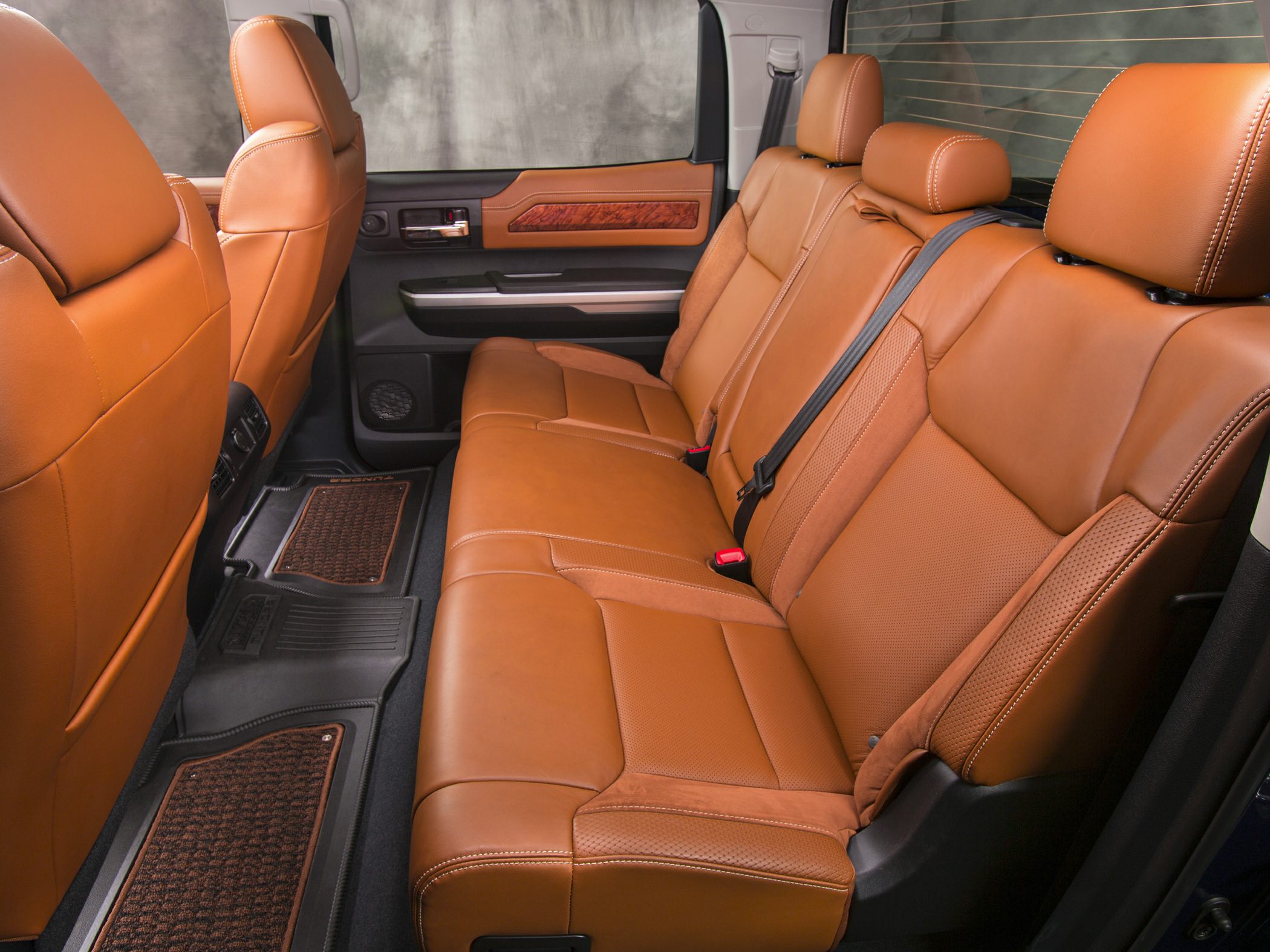 Tan leather rear seats with detailed stitching and spacious cabin.