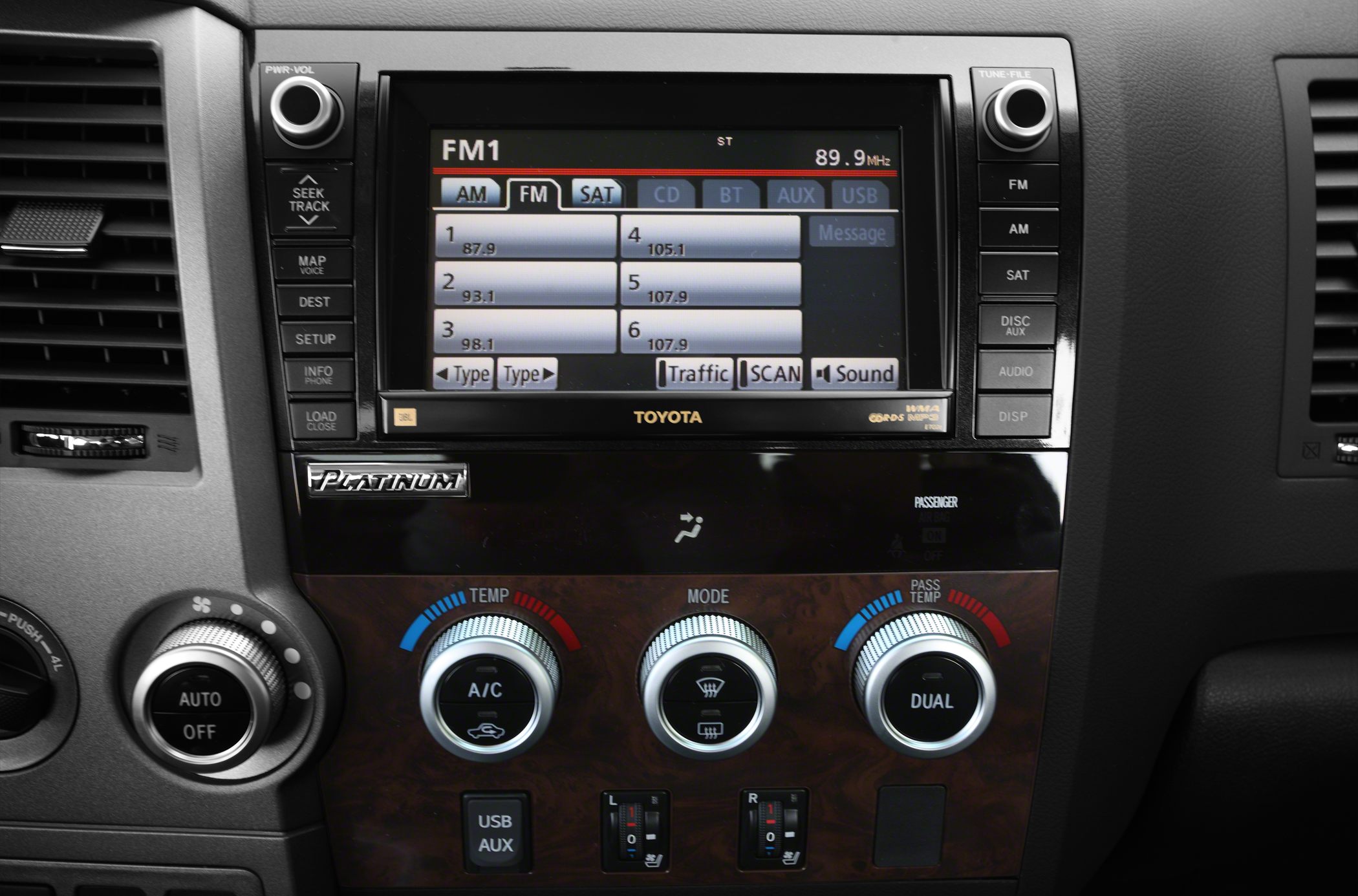 Infotainment screen with radio presets and climate control knobs