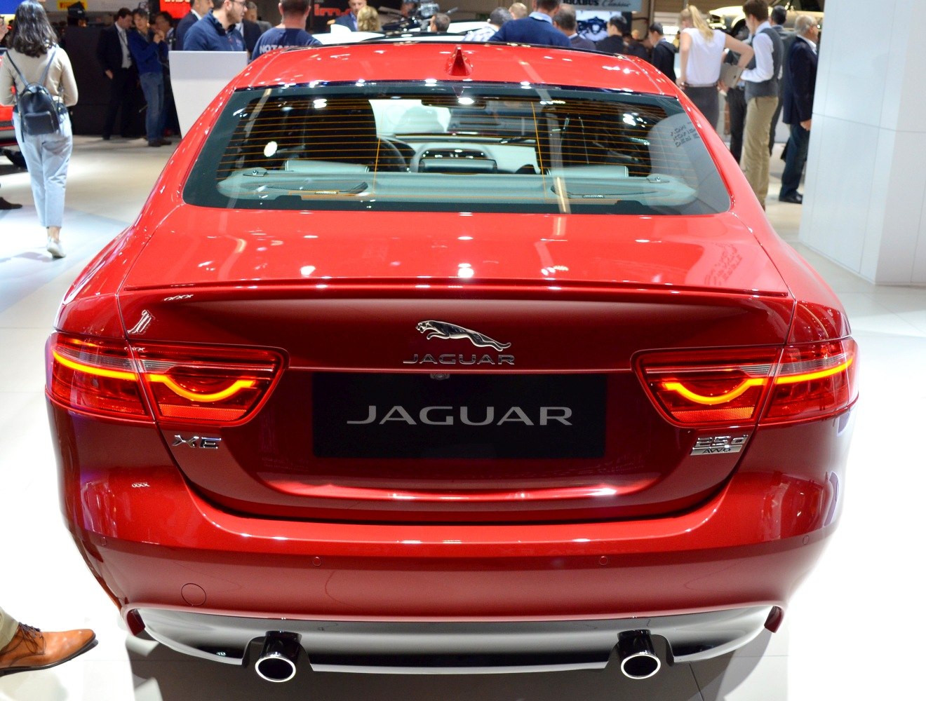 Red car rear with illuminated tail lights and dual exhaust pipes.