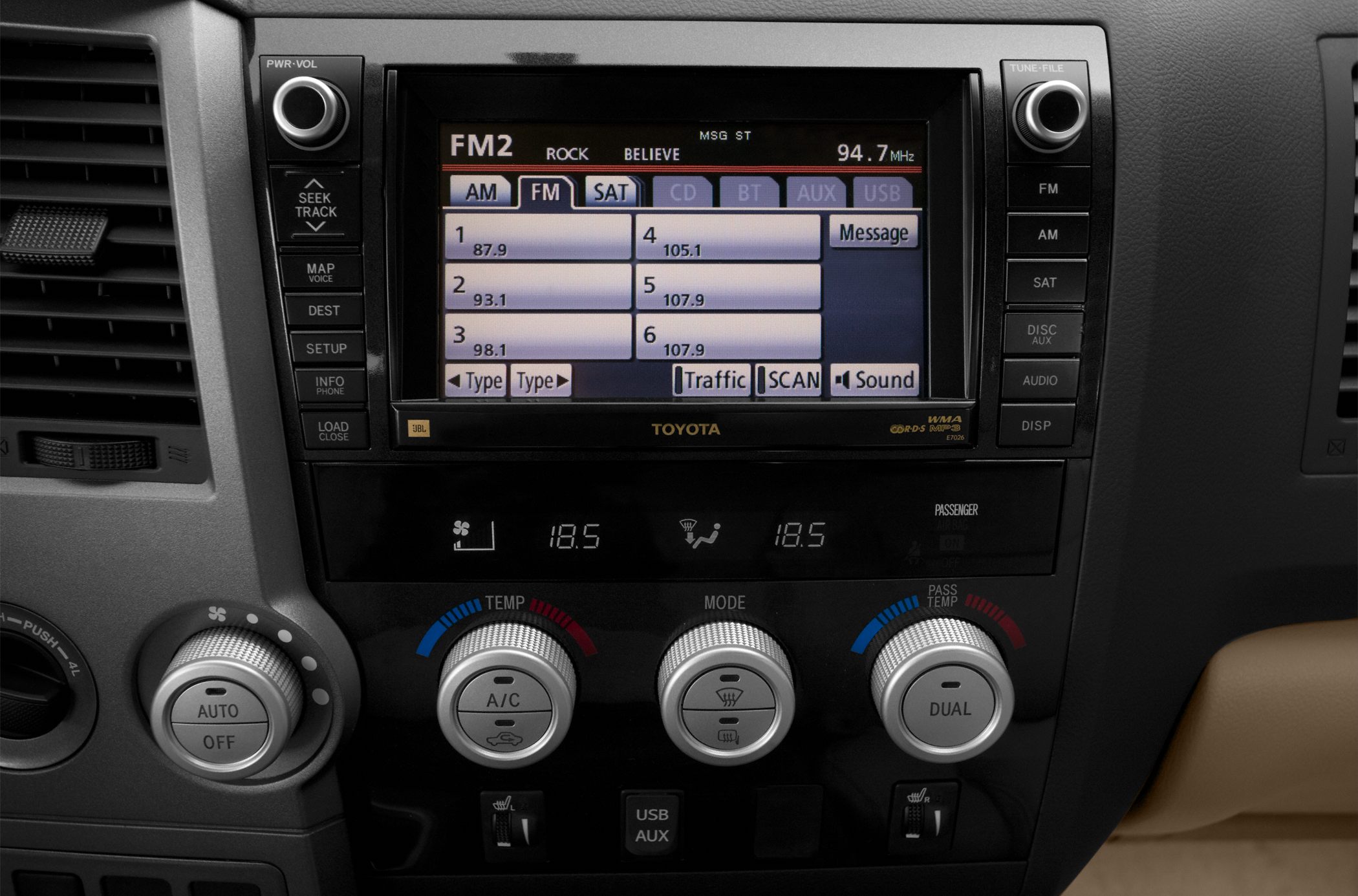 Infotainment screen with radio presets and dual-zone climate control knobs