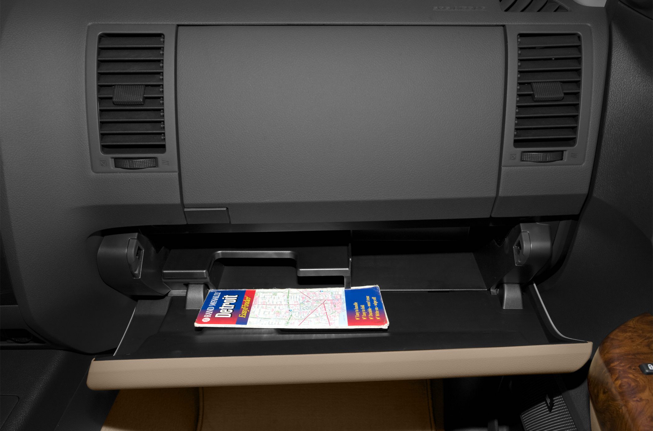 Open glove compartment with a map inside and dashboard air vents
