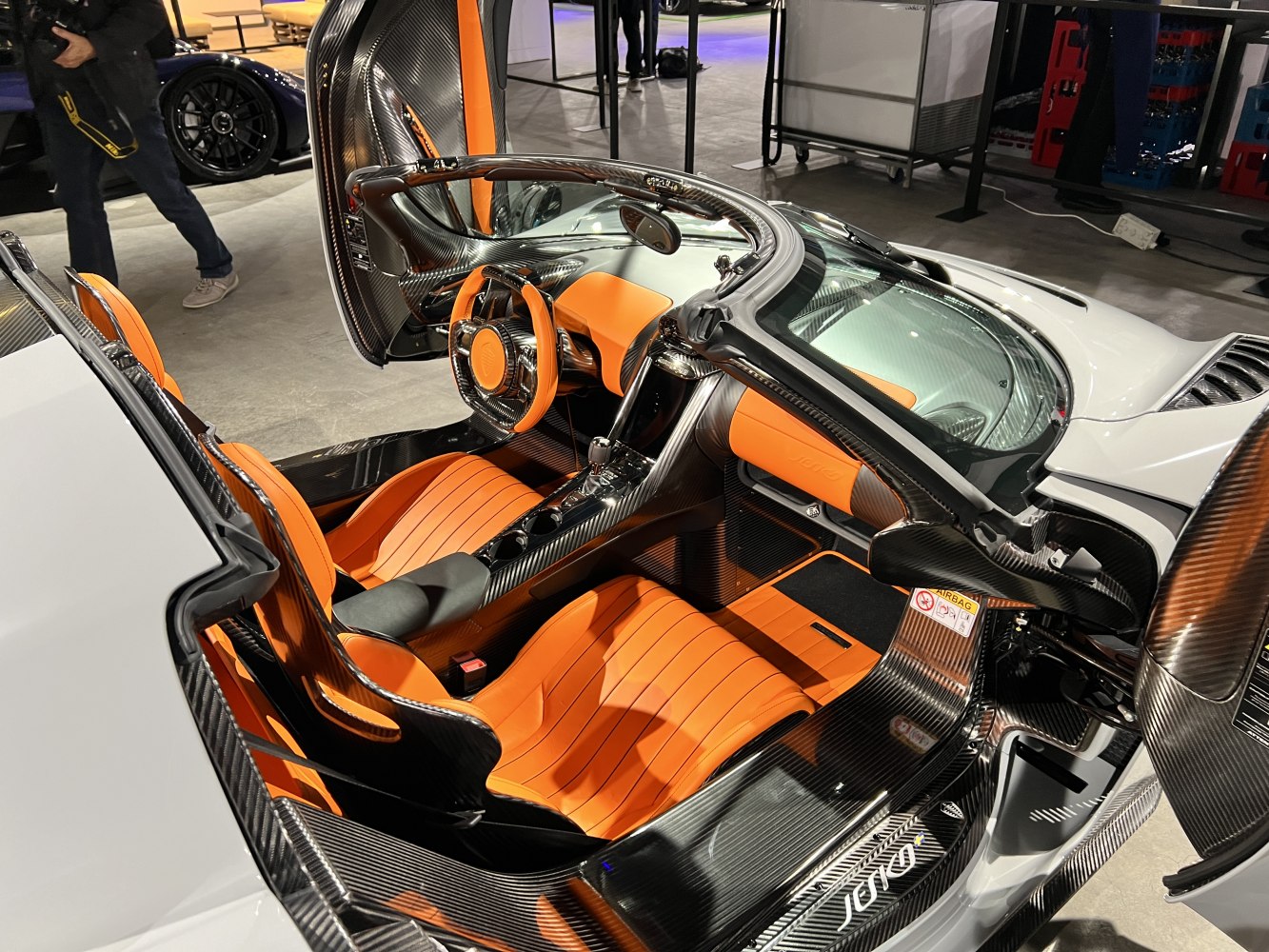 Open door reveals carbon fiber and orange leather sports cockpit.