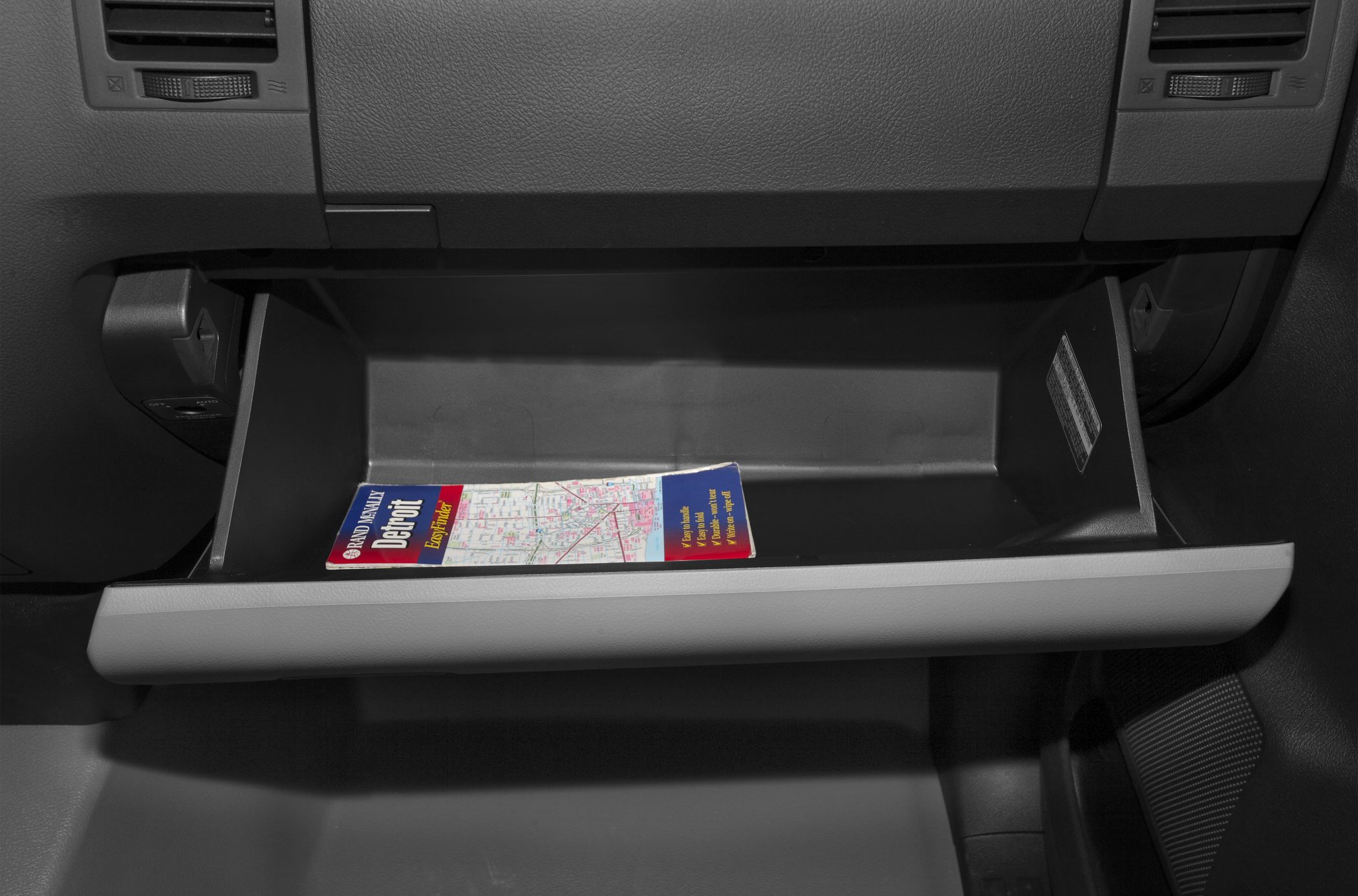 Open glove compartment with a folded map inside.