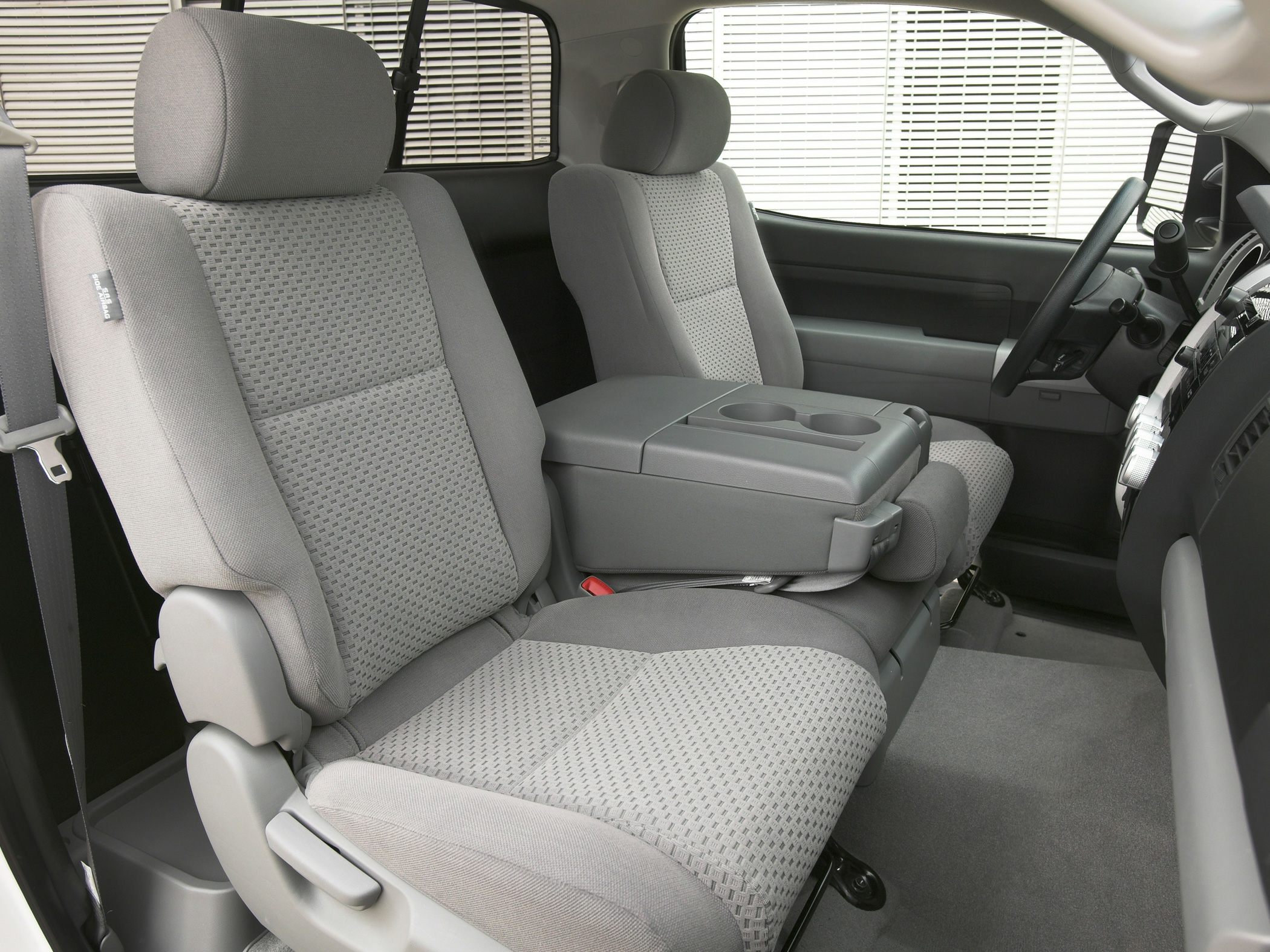 Spacious front seats with center armrest and cup holders in vehicle interior