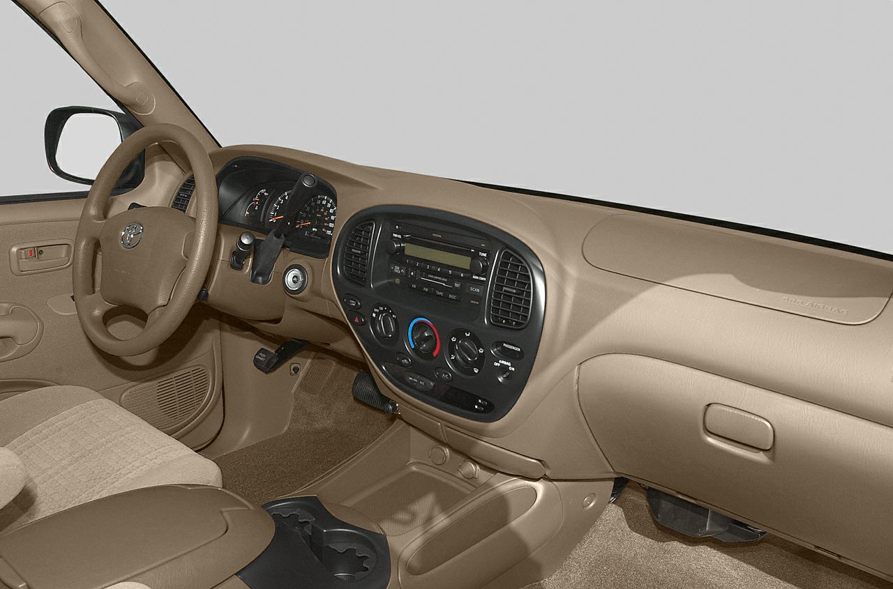 Beige dashboard and steering wheel with analog gauges and basic radio controls