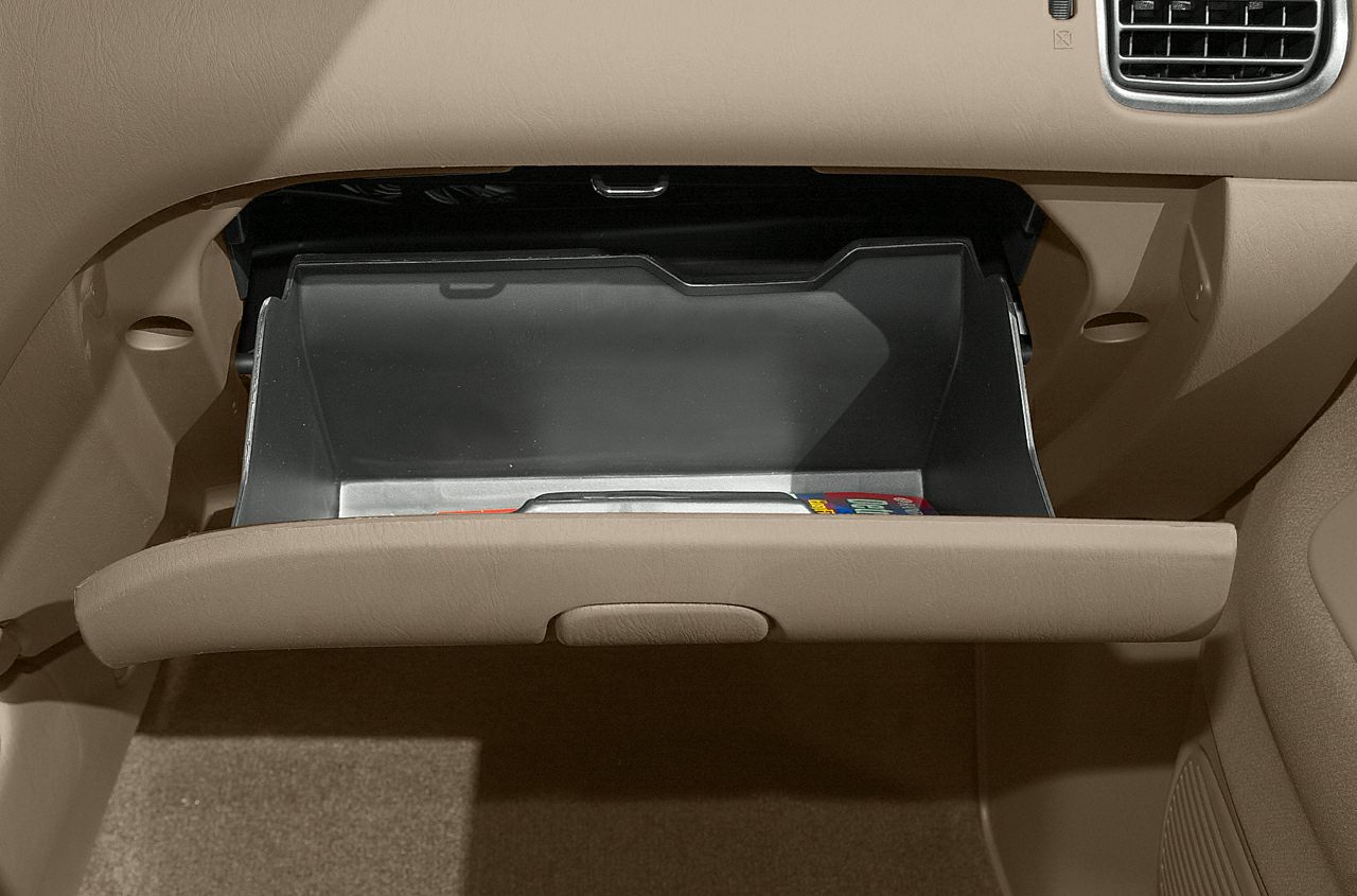 Open glove compartment with beige trim and minimal contents