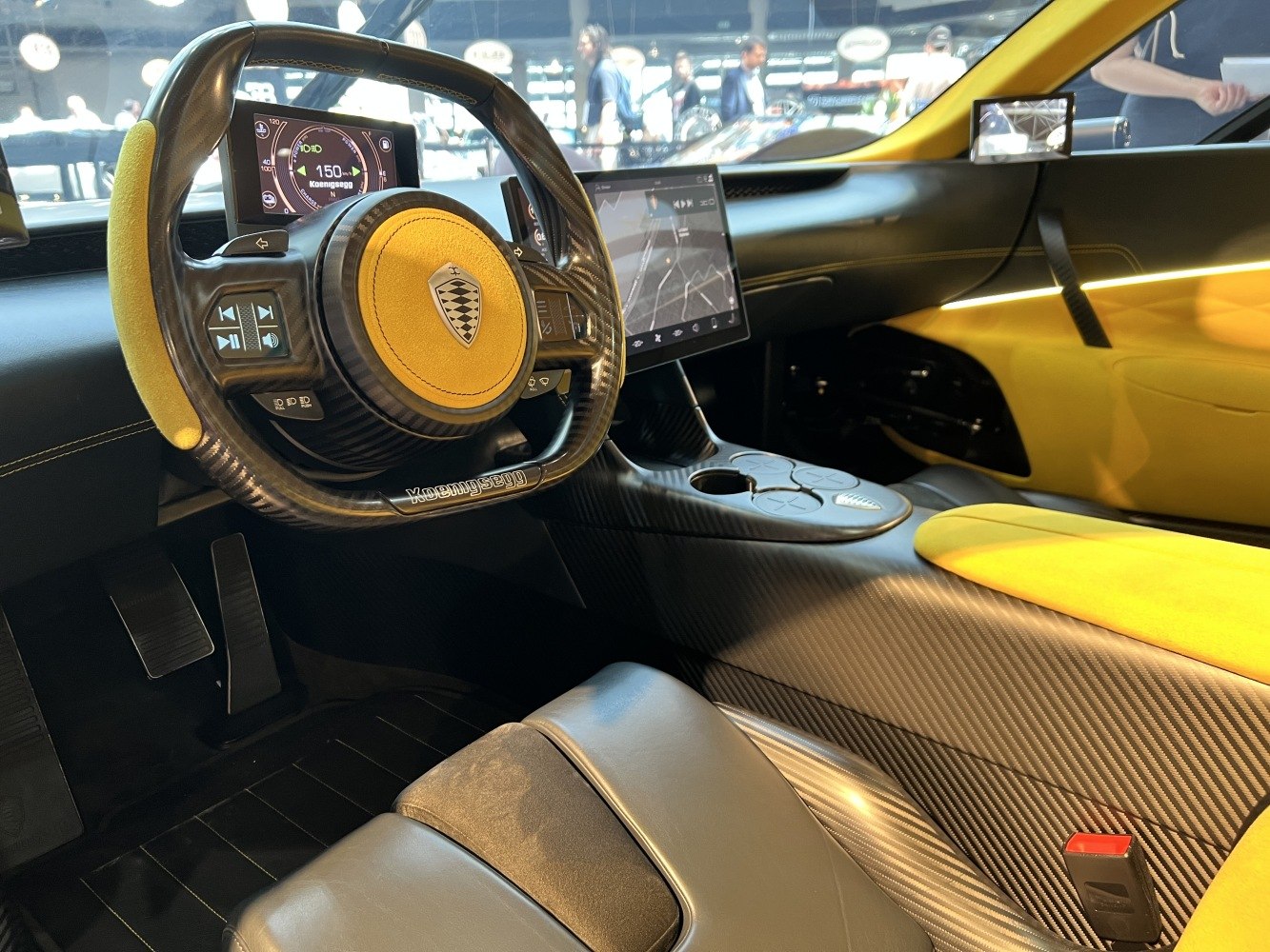 Carbon fiber steering wheel with digital displays and touchscreen infotainment.