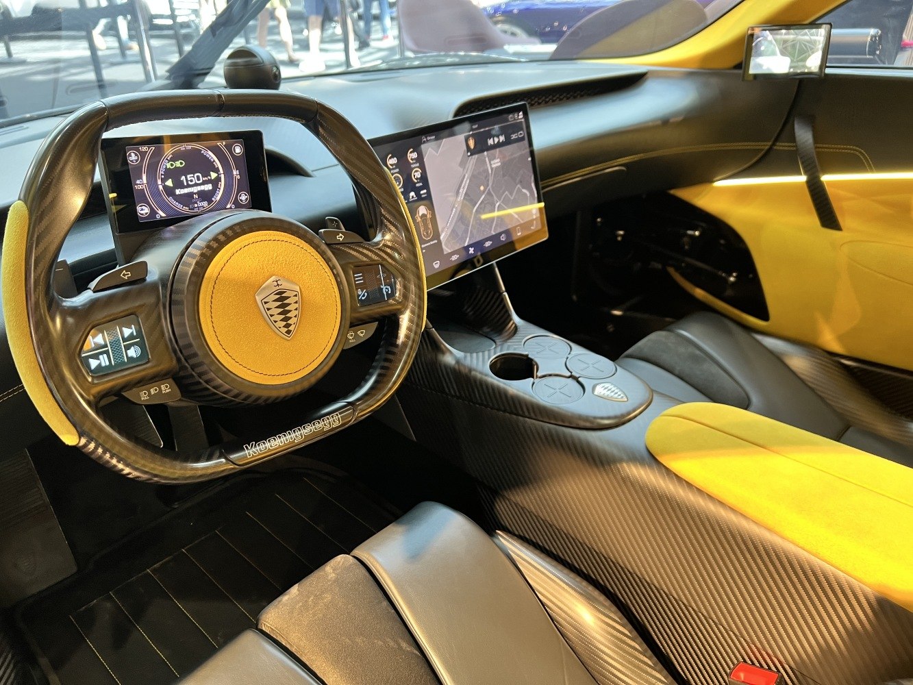 Carbon fiber steering wheel with digital dashboard and touchscreen displays.